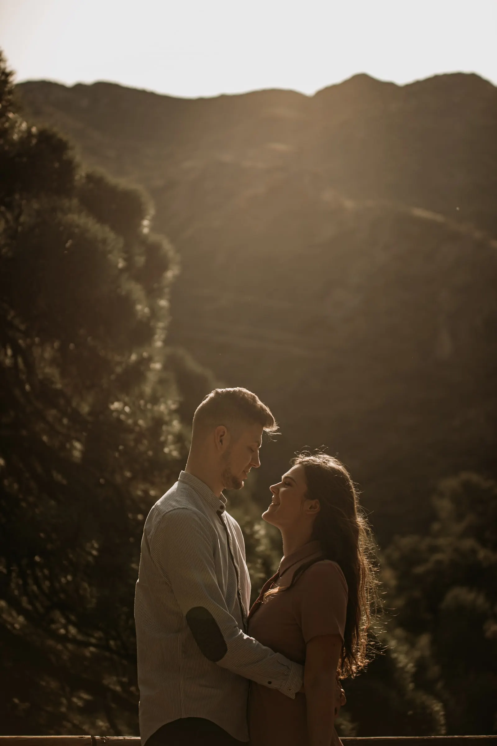 Couple about to kiss in the backlight, a steep wooded valley behind, Costa del Sol