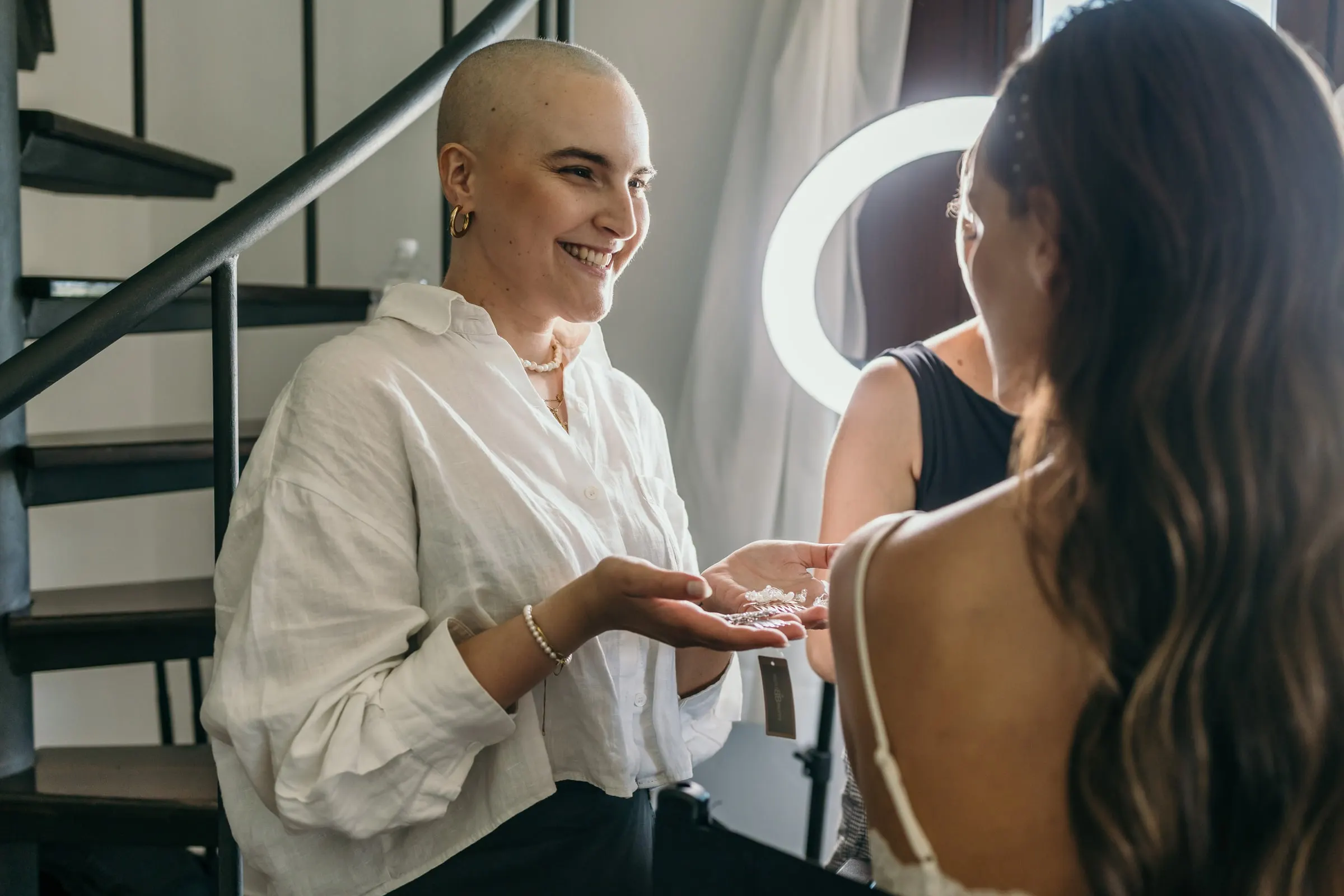 Friend in a linen shirt showing the bride a pair of earrings in her palm