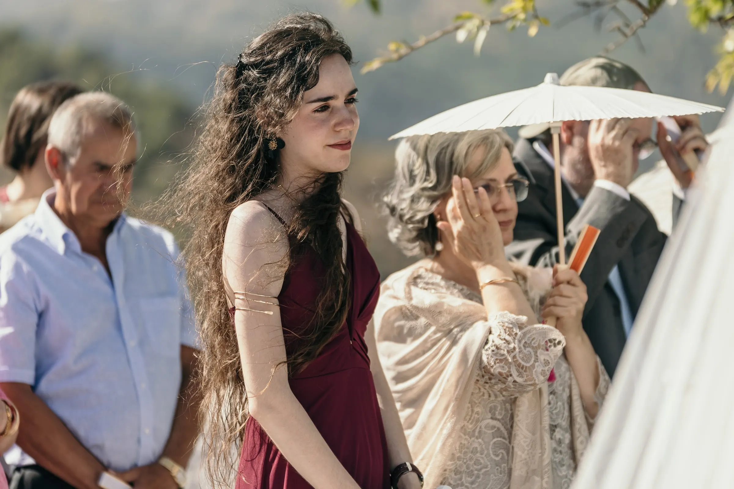 Guests moved during the ceremony, a woman wiping her eyes under a paper parasol