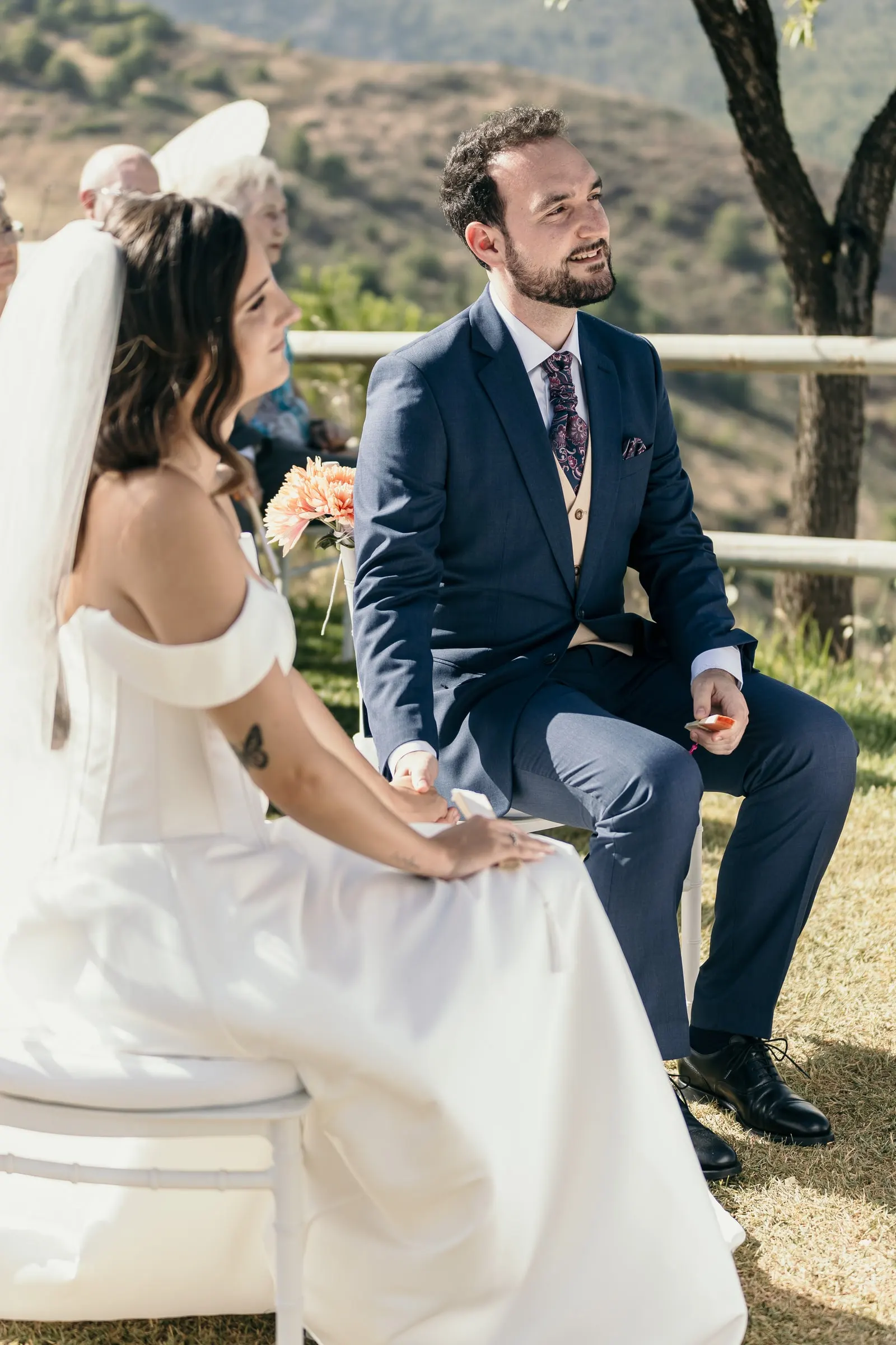Bride and groom seated during the ceremony with the mountains behind them