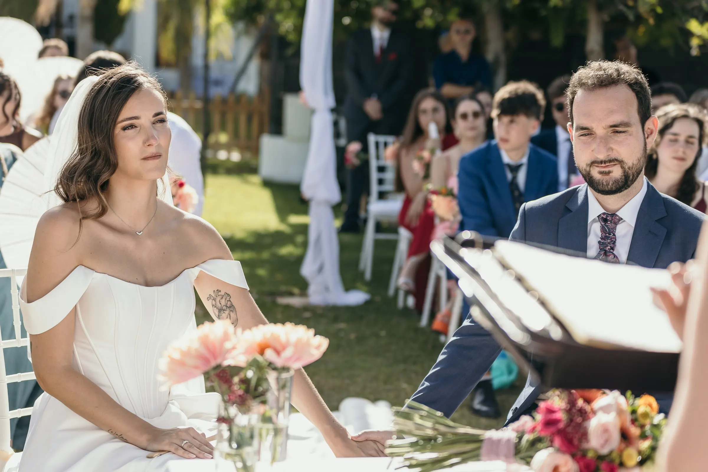 Bride and groom listening at the ceremony table decorated with pink gerberas