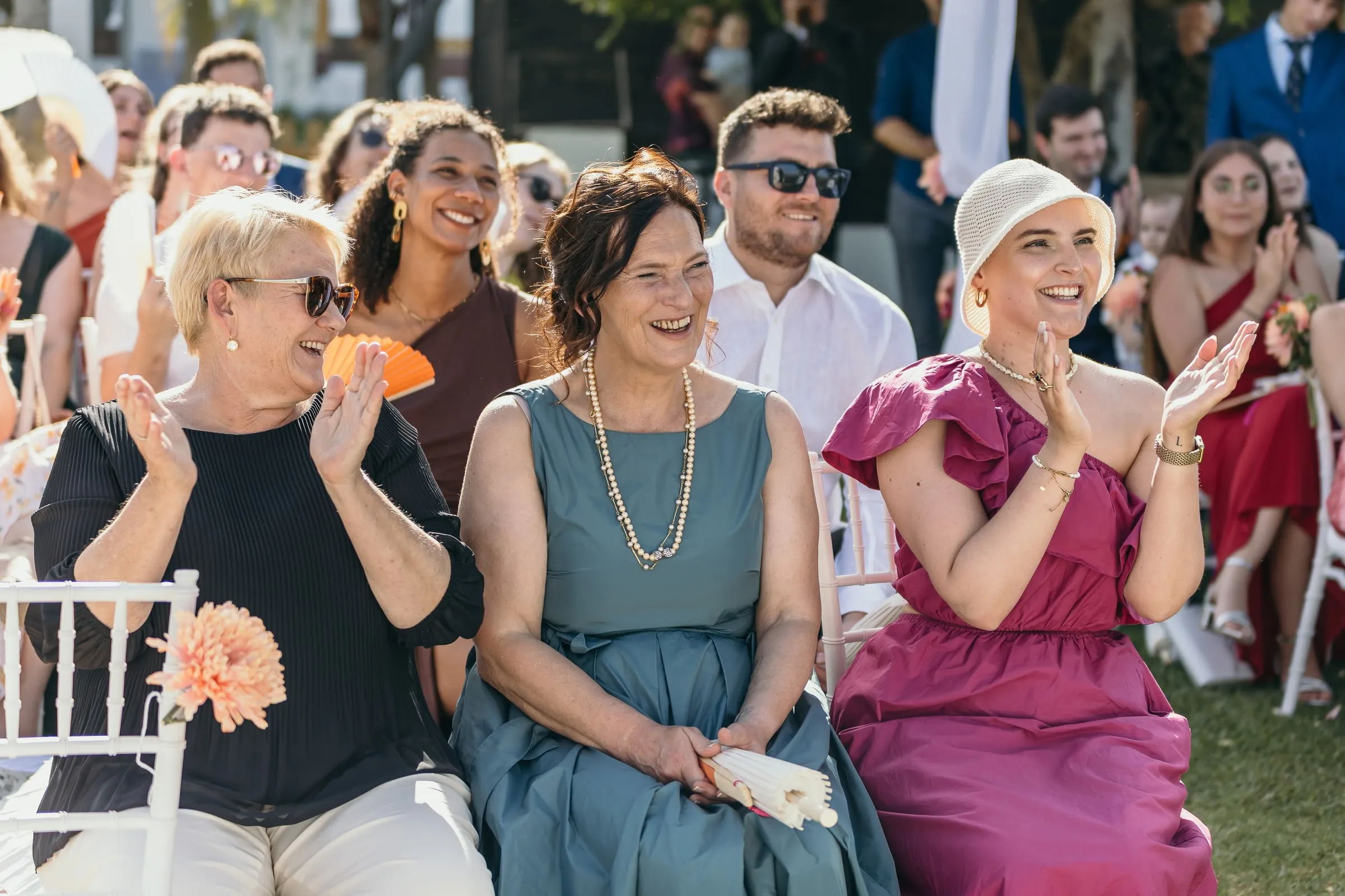 Three women in the front row applauding and laughing after the vows