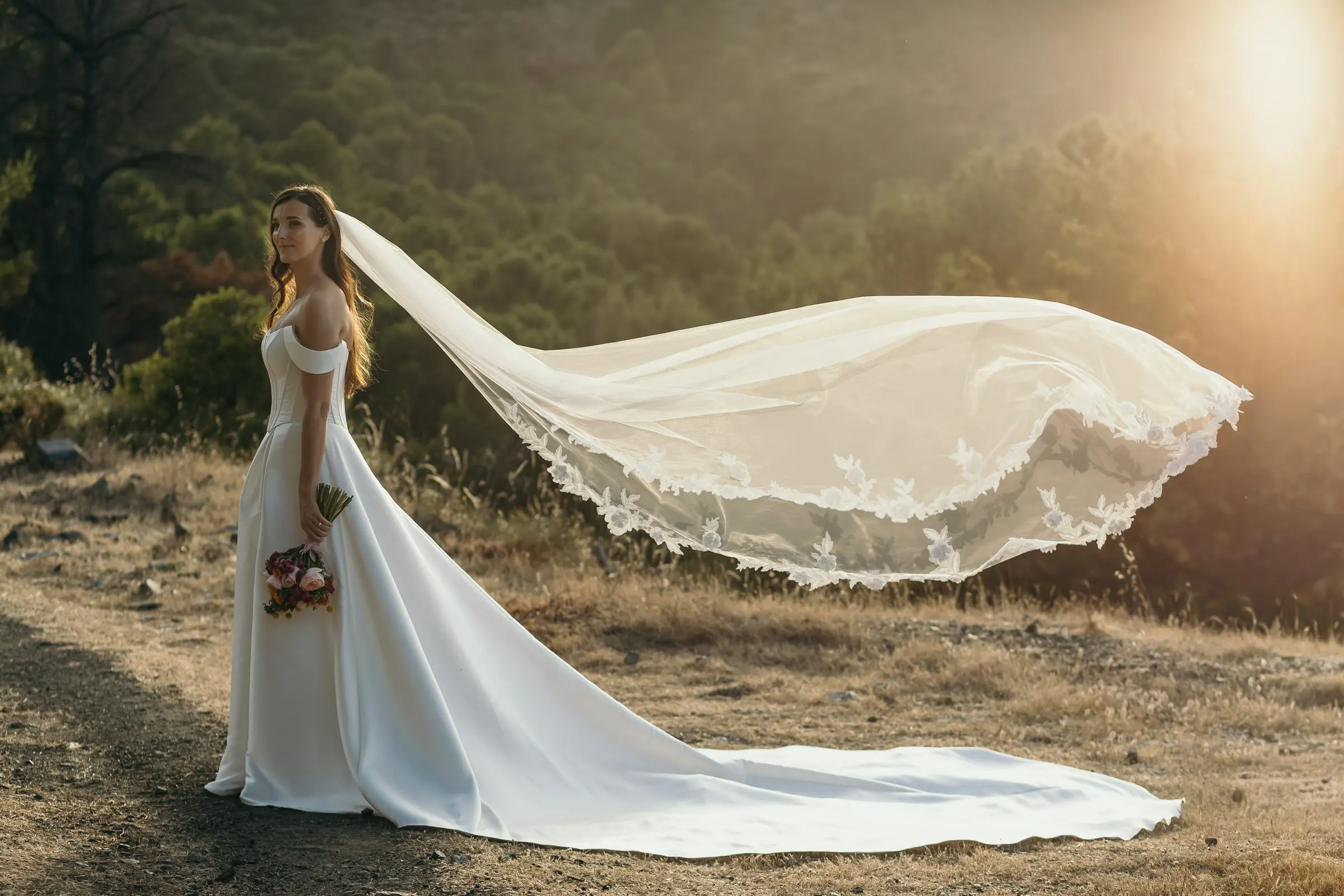 Bride's veil flying in the wind at sunset on a dry hillside