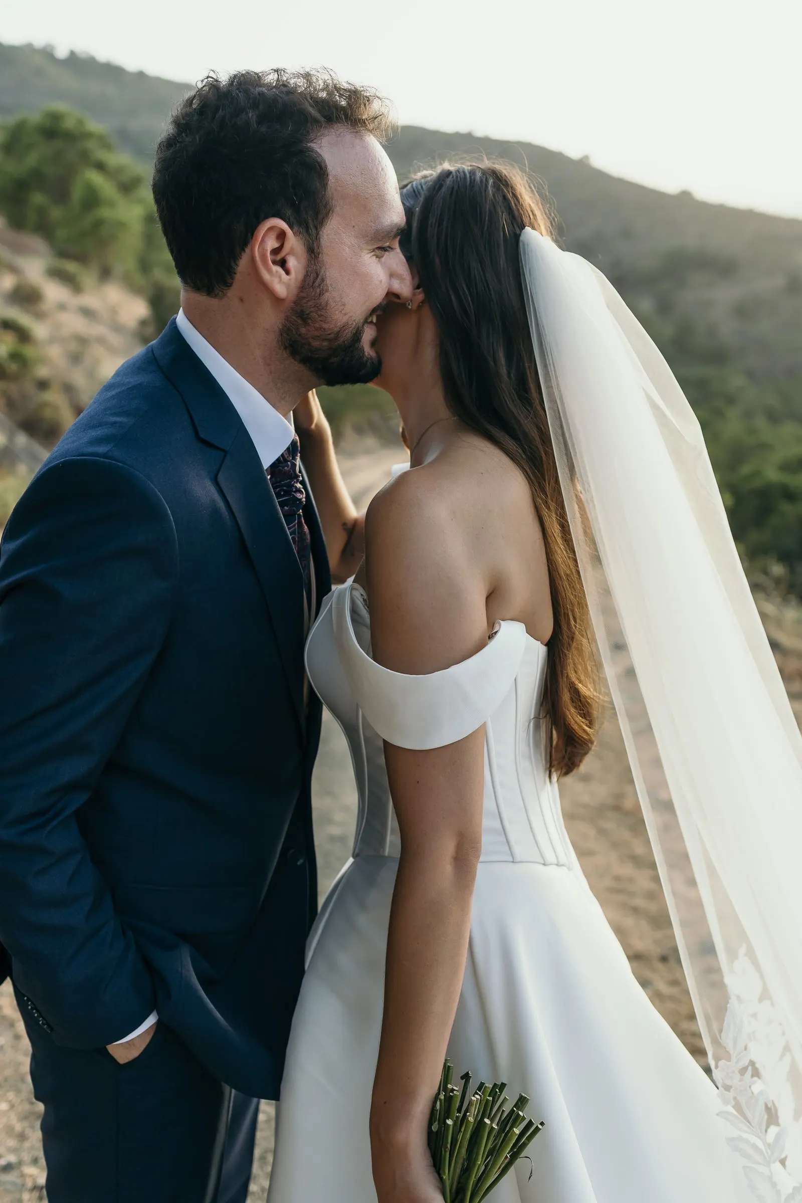 Groom kissing the bride's cheek at sunset in the mountains