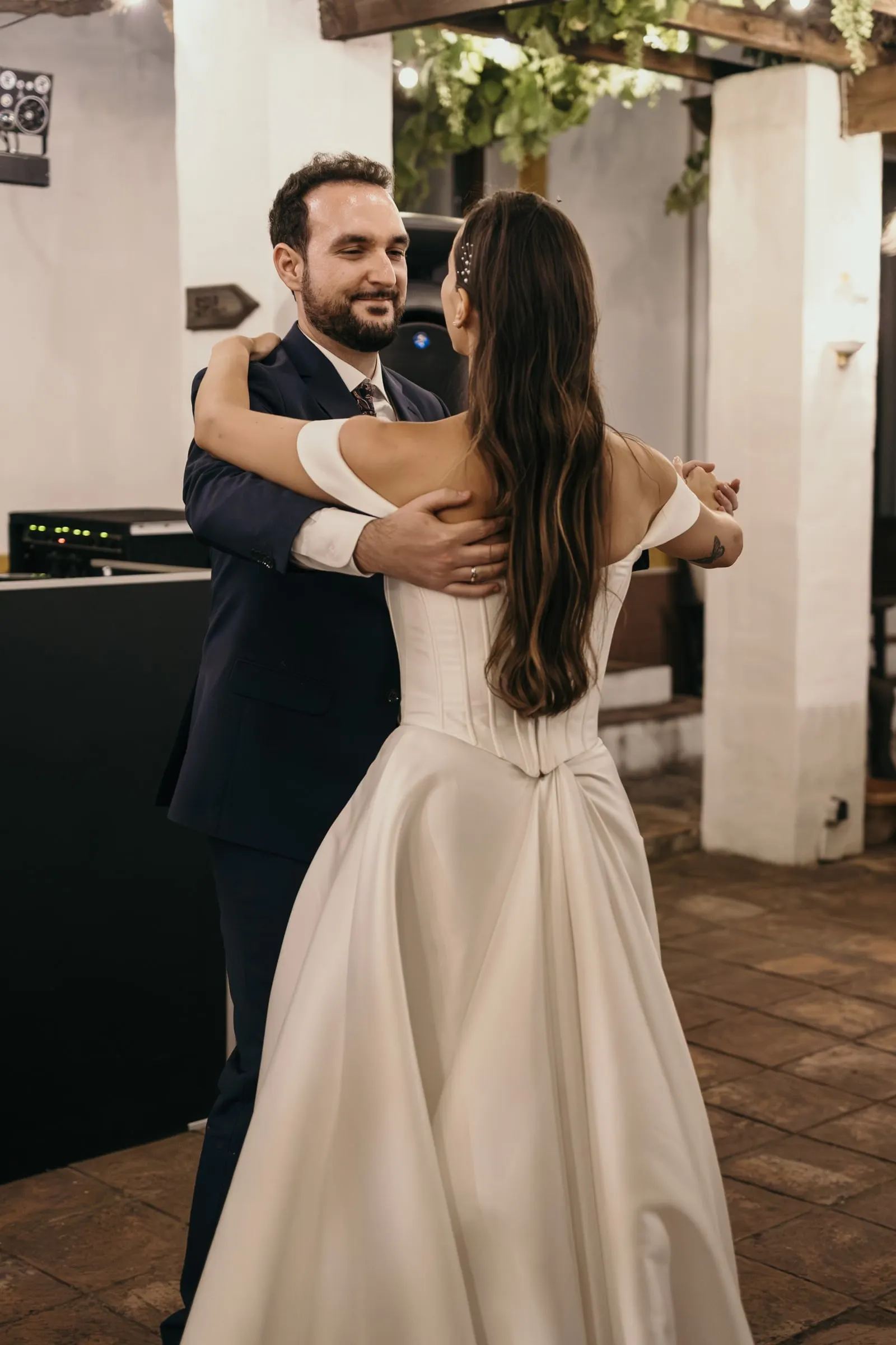 Bride and groom embracing during their first dance under the whitewashed porch