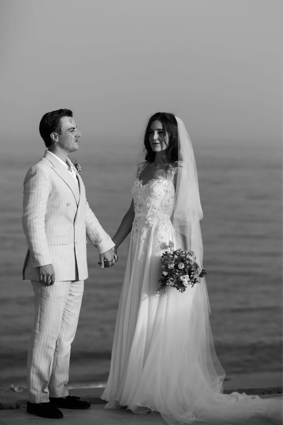 Los novios cogidos de la mano con el mar a su espalda, en blanco y negro, Barbillón, Marbella
