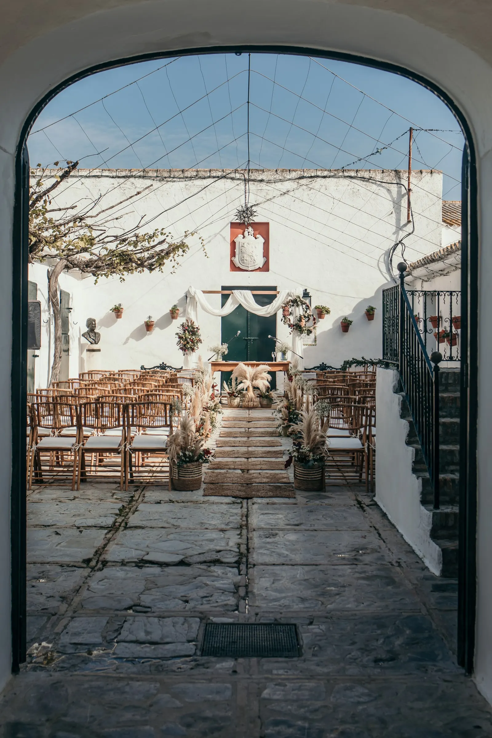 Whitewashed courtyard set with wooden chairs, seen through an arch, Finca Espanta Rodrigo, Jerez de la Frontera