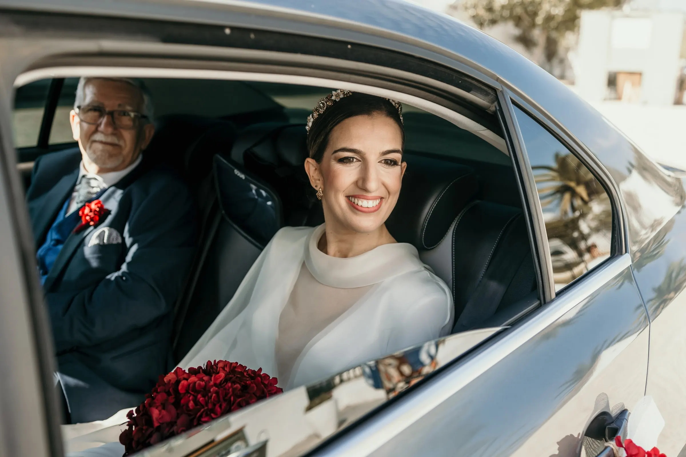Bride smiling from the back seat of the wedding car beside her father on arrival at the cortijo