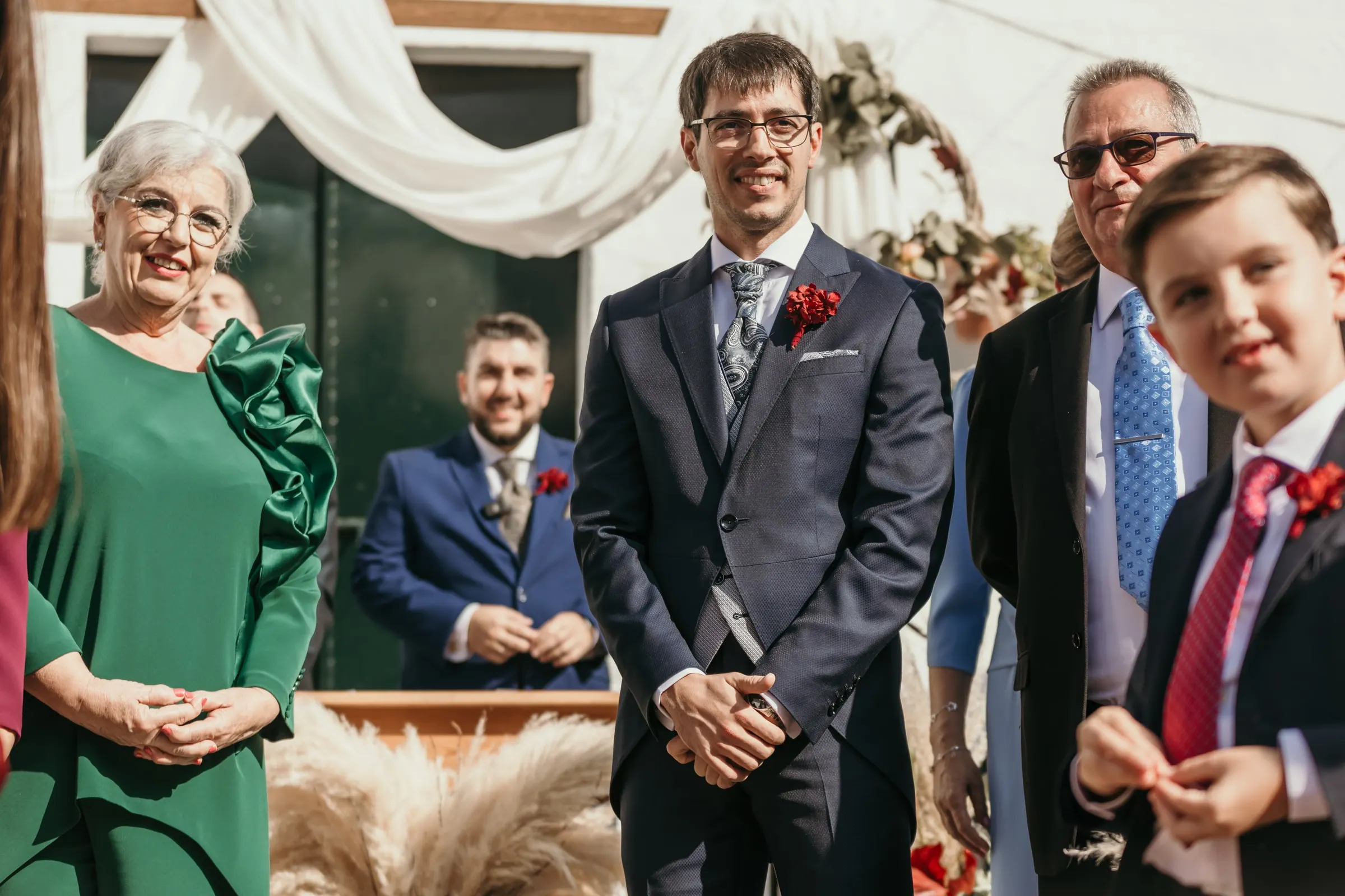 Groom and his family smiling at the front of the ceremony as the bride arrives in the Andalusian courtyard