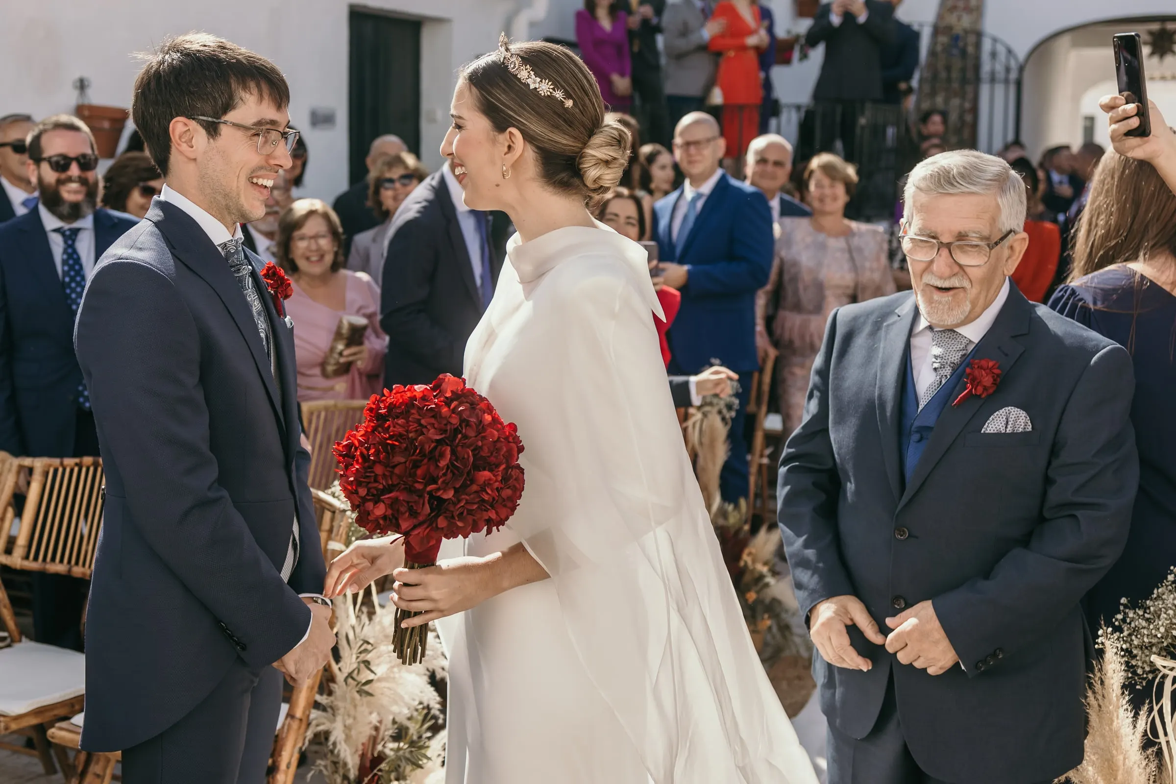 Bride meeting the groom at the end of the aisle while her father looks on, Andalusian cortijo wedding