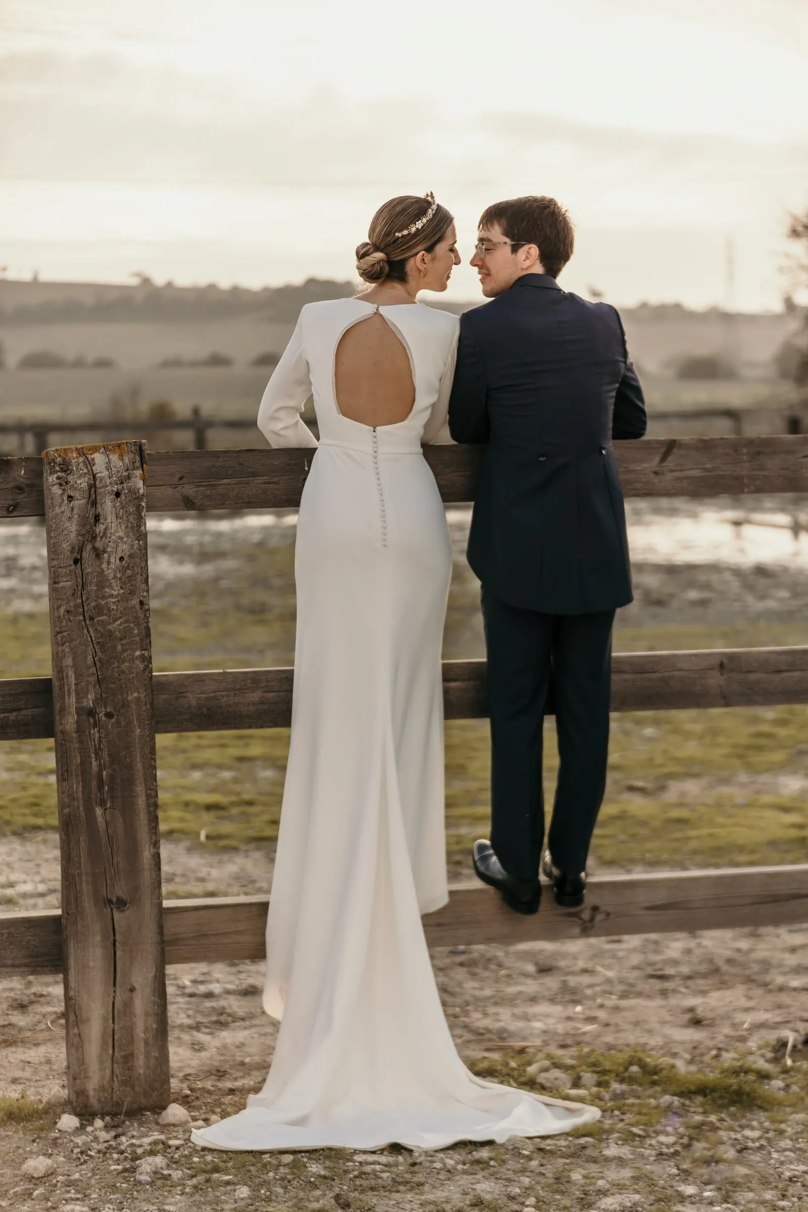Couple leaning on a wooden fence looking out over the open countryside around the cortijo