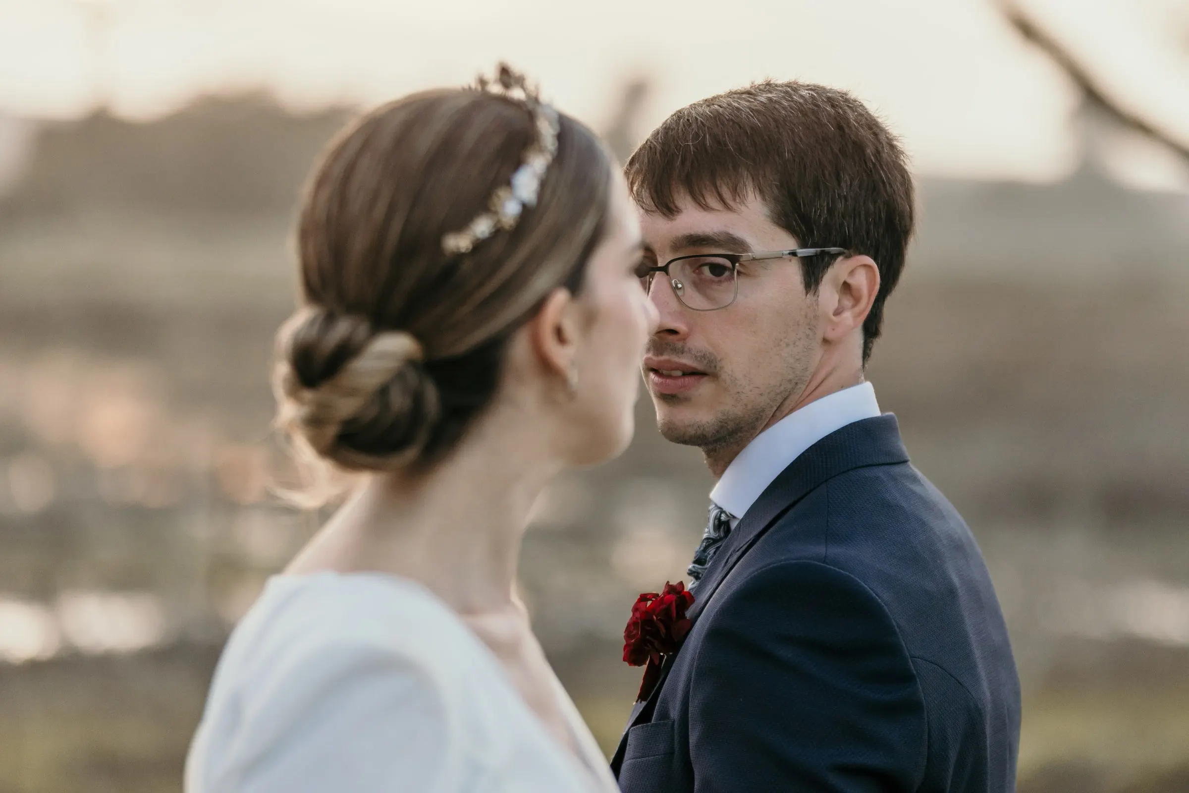 Bride with a pearl headband looking at the groom against the hazy Andalusian countryside