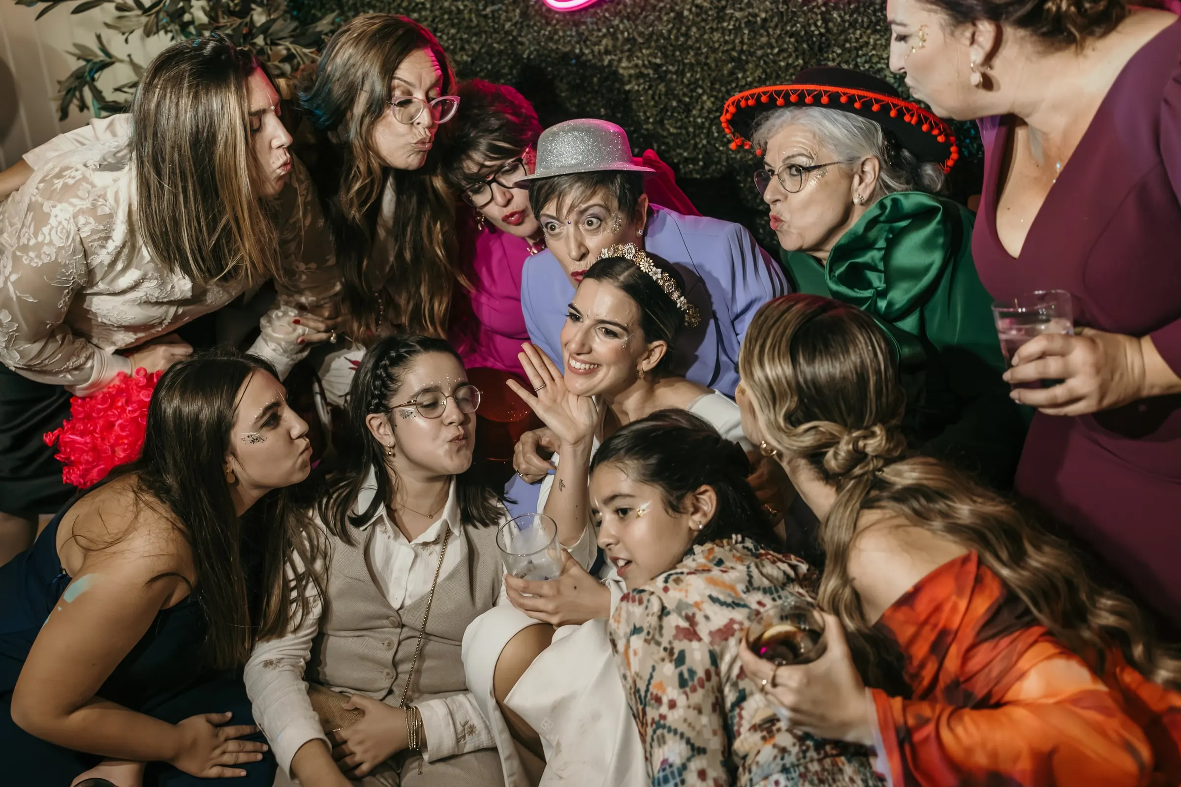 Friends crowding together for a photo with props and party hats at the wedding party