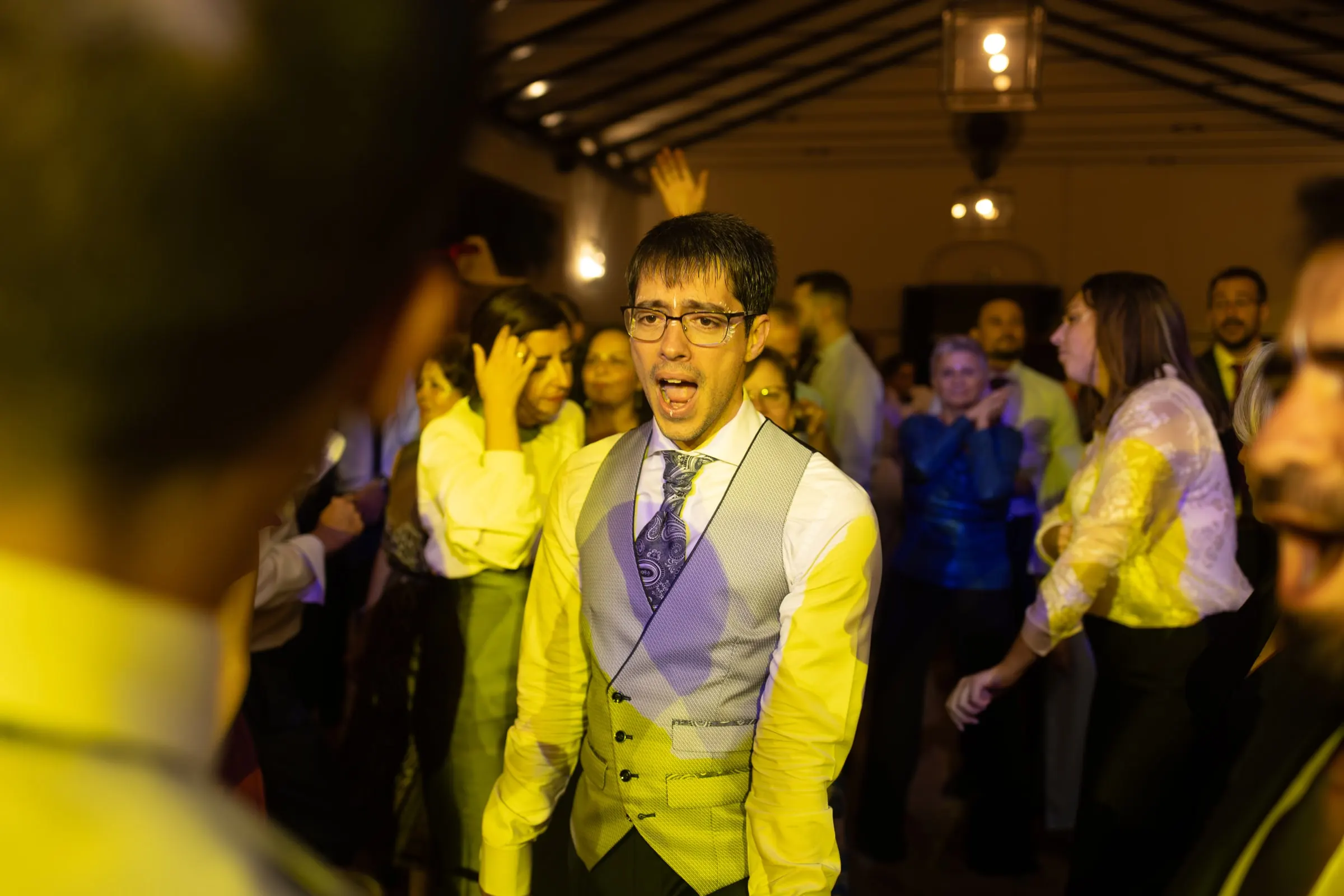 Groom dancing under yellow party lights in the cortijo banquet hall