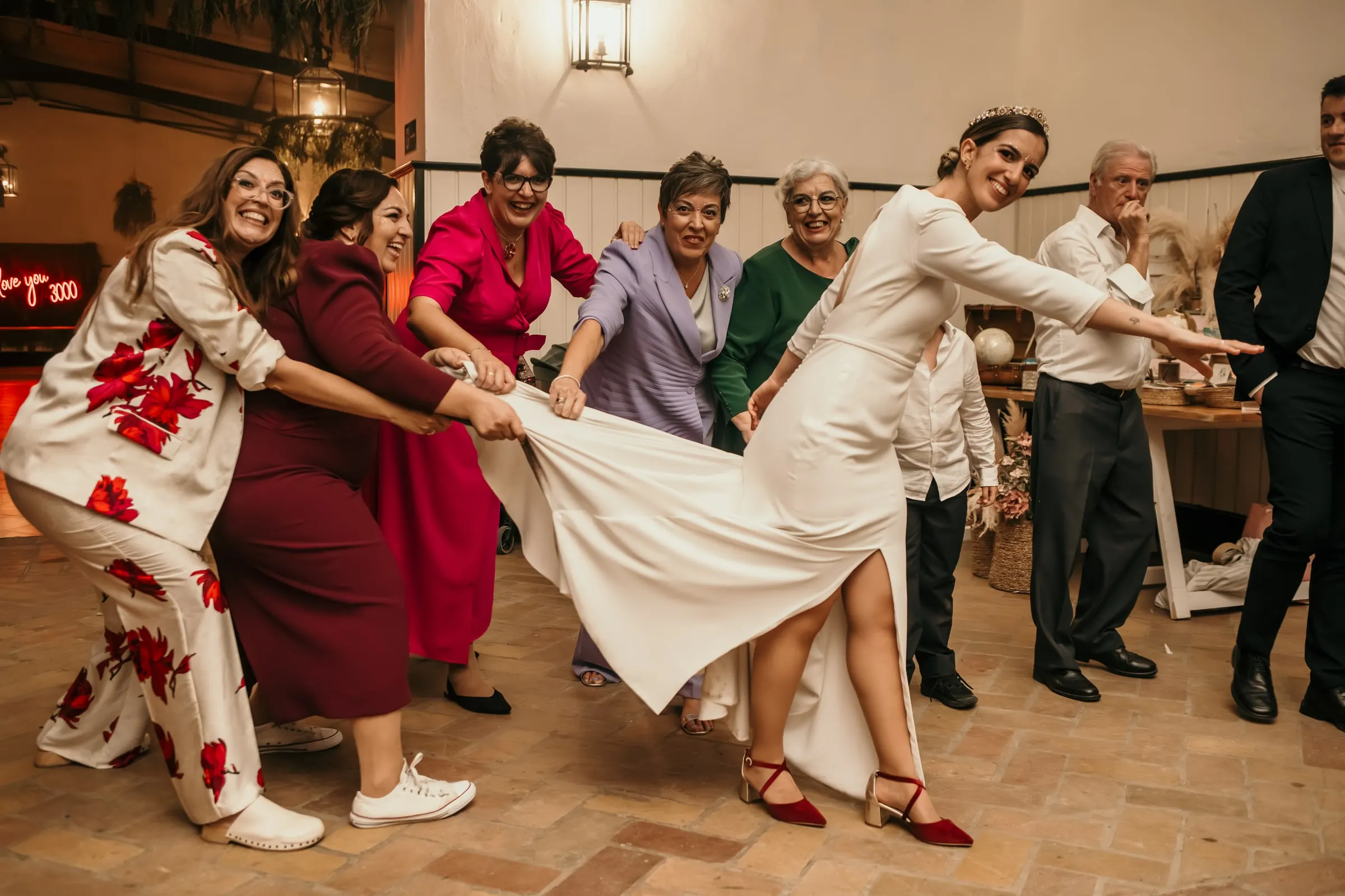 Guests pulling the bride along by her train in a line dance across the terracotta floor