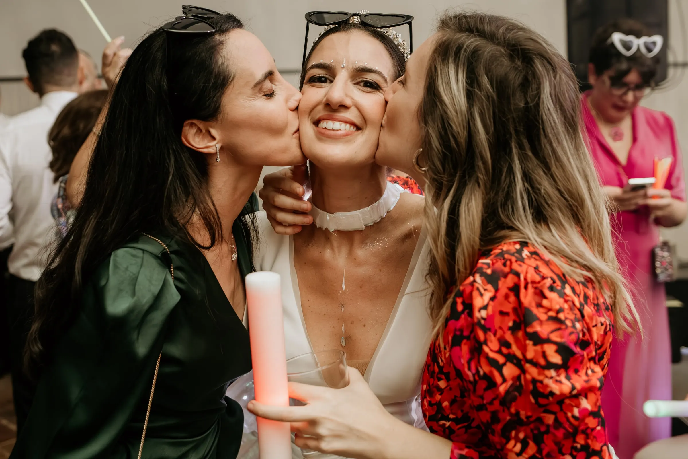 Two friends kissing the bride on both cheeks at the end of the party