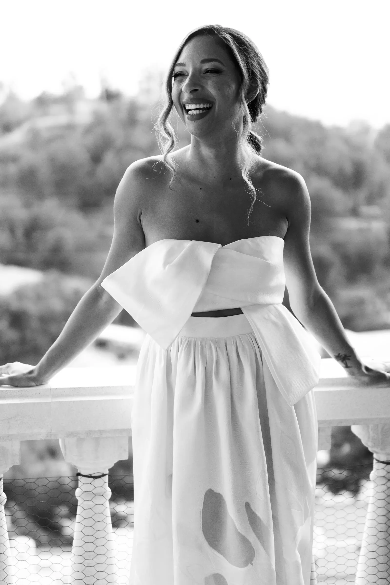 Foto en blanco y negro de la novia riendo apoyada en la barandilla del balcón