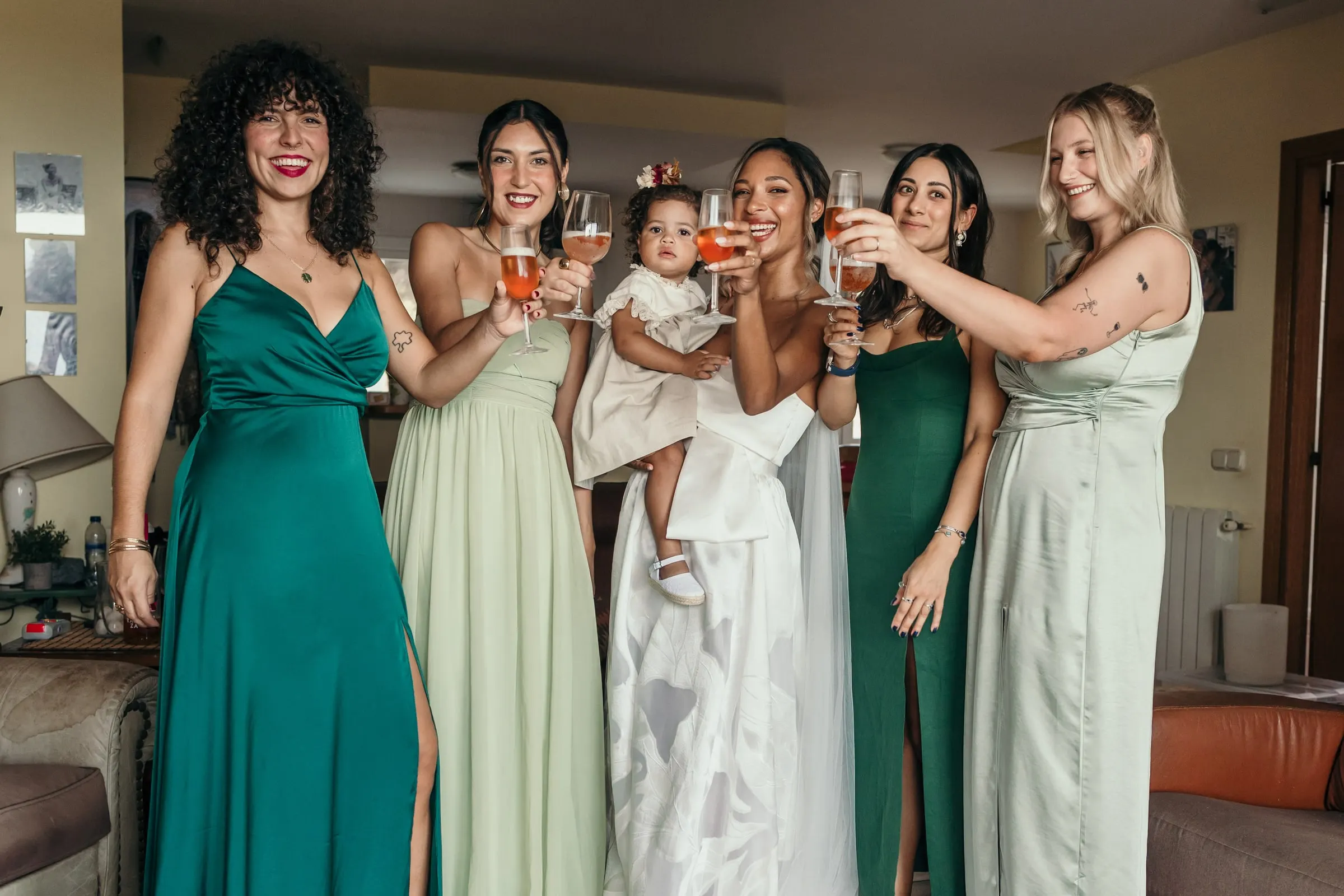 Las damas de verde y salvia brindan con la novia y la niña en el salón