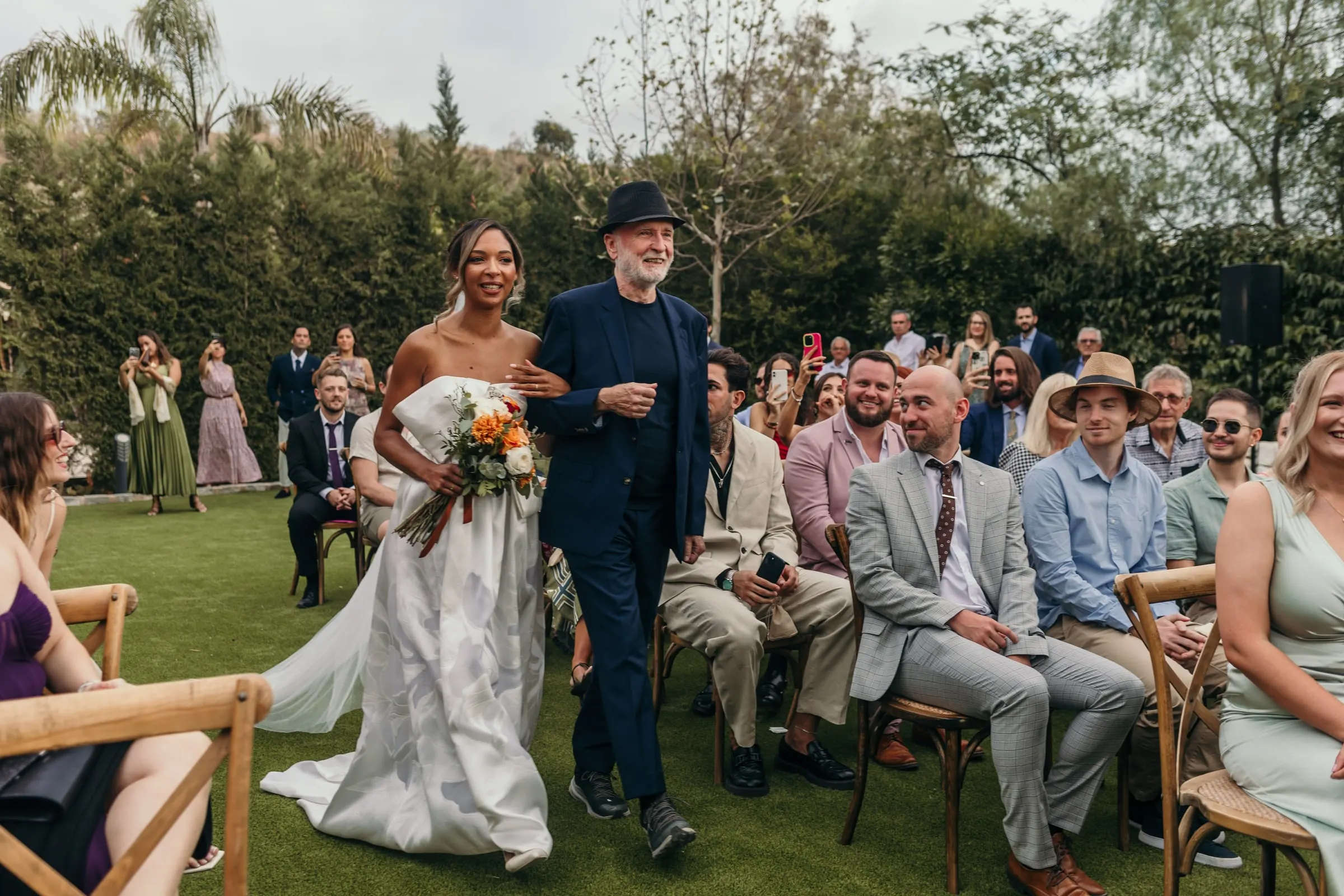 Vista amplia de la novia avanzando por el pasillo entre los invitados en el jardín