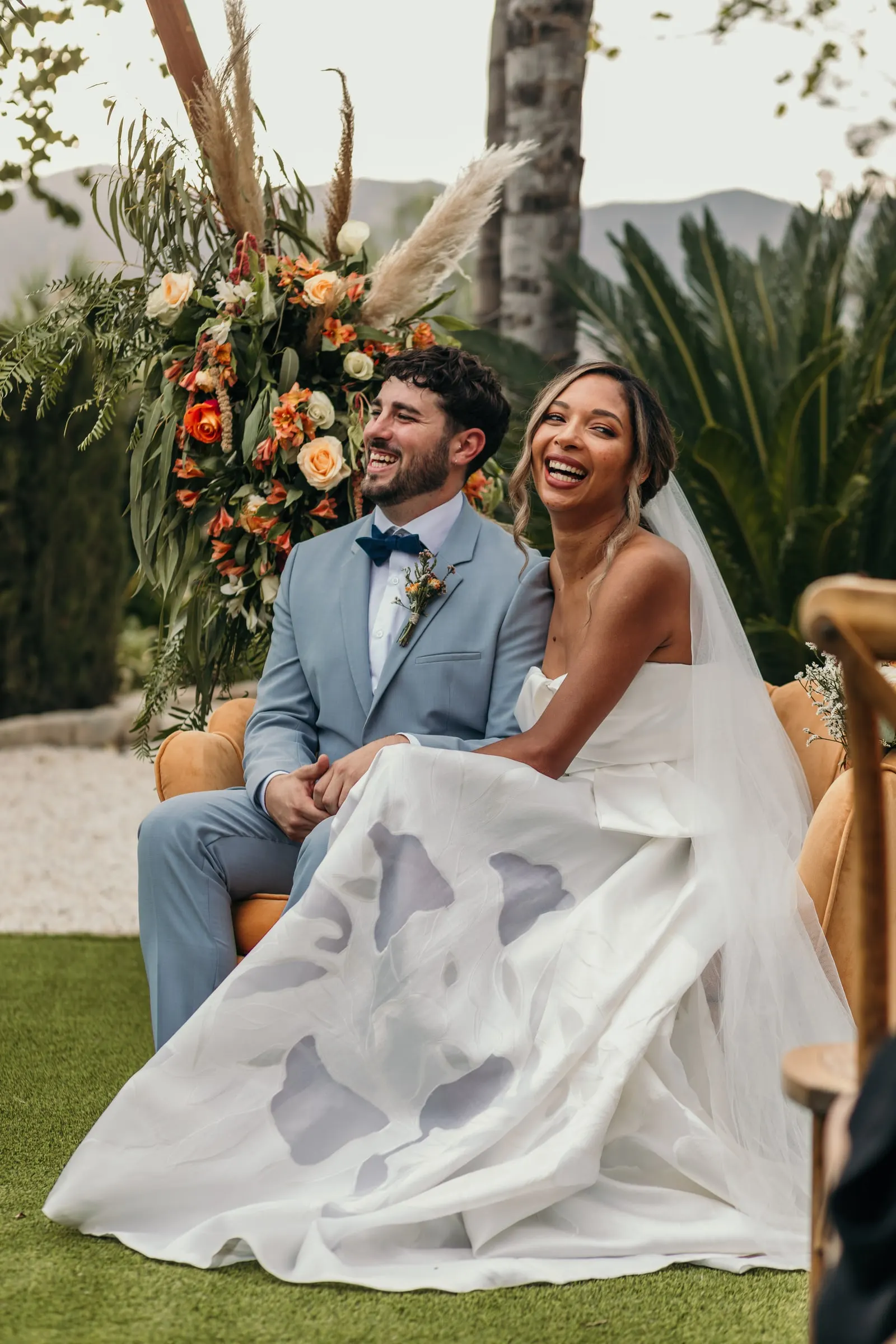 Los novios ríen en la ceremonia bajo la hierba de la pampa y las rosas naranjas