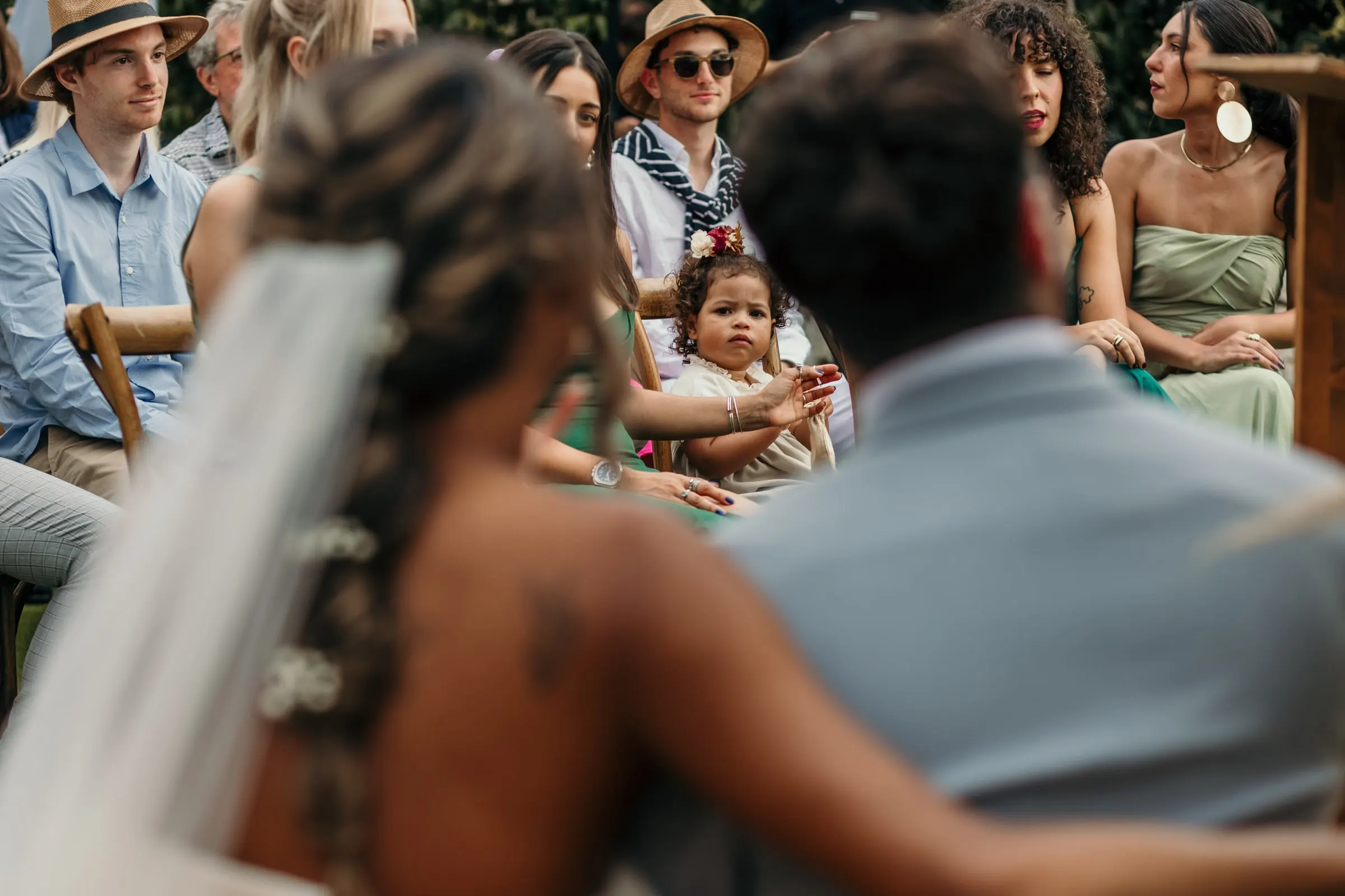El velo y la trenza de la novia en primer plano mientras mira a los invitados