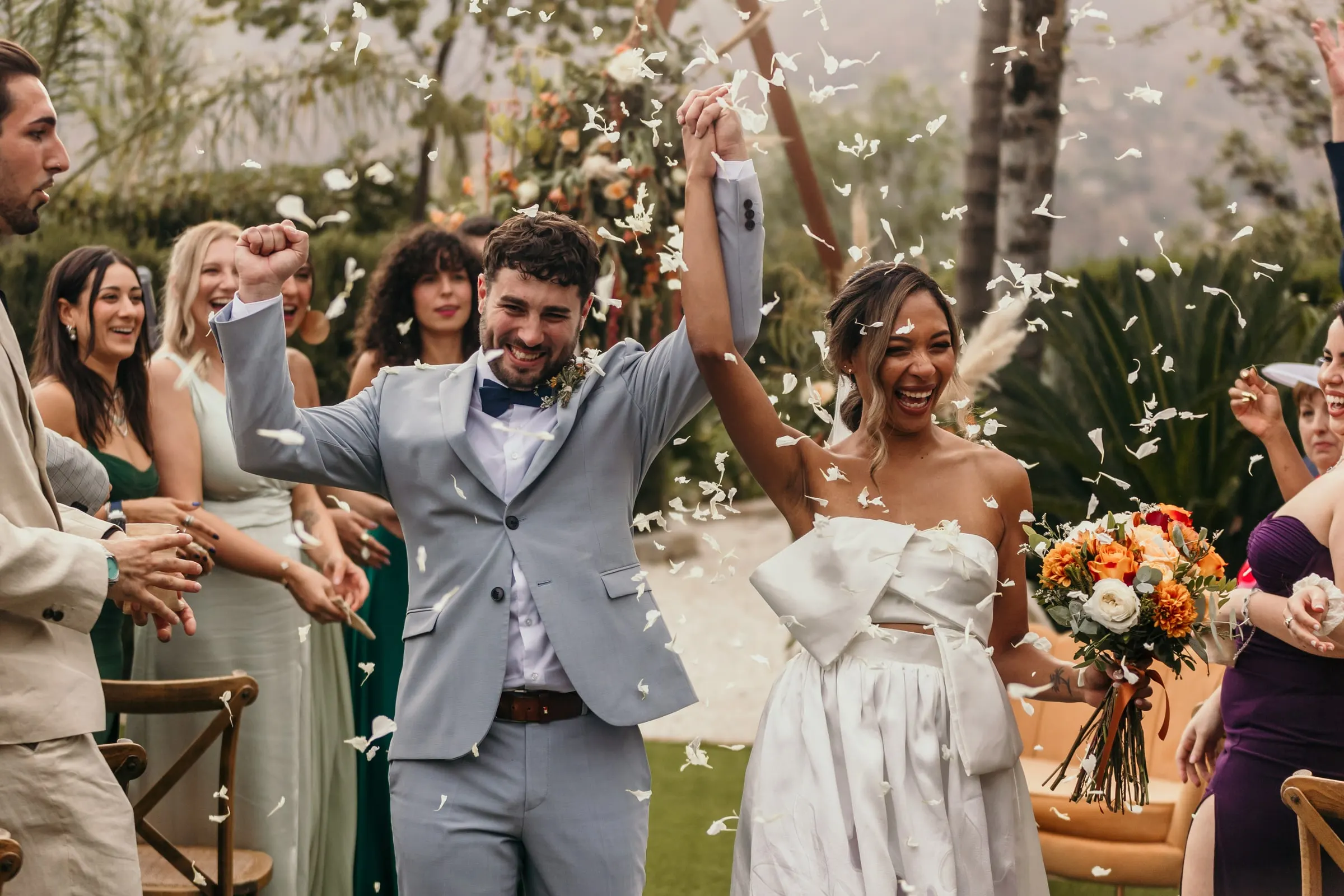 Los recién casados lo celebran mientras los invitados les lanzan pétalos al final de la ceremonia