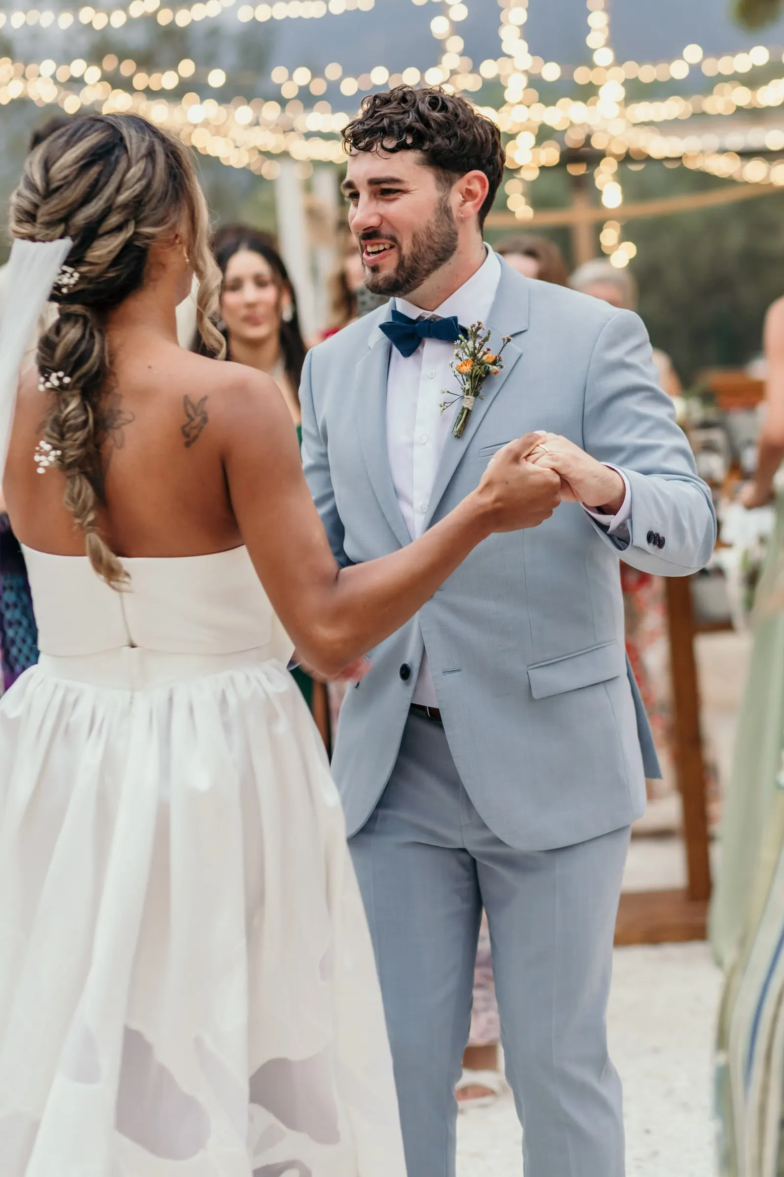 Los novios bailan de la mano bajo las guirnaldas de luces