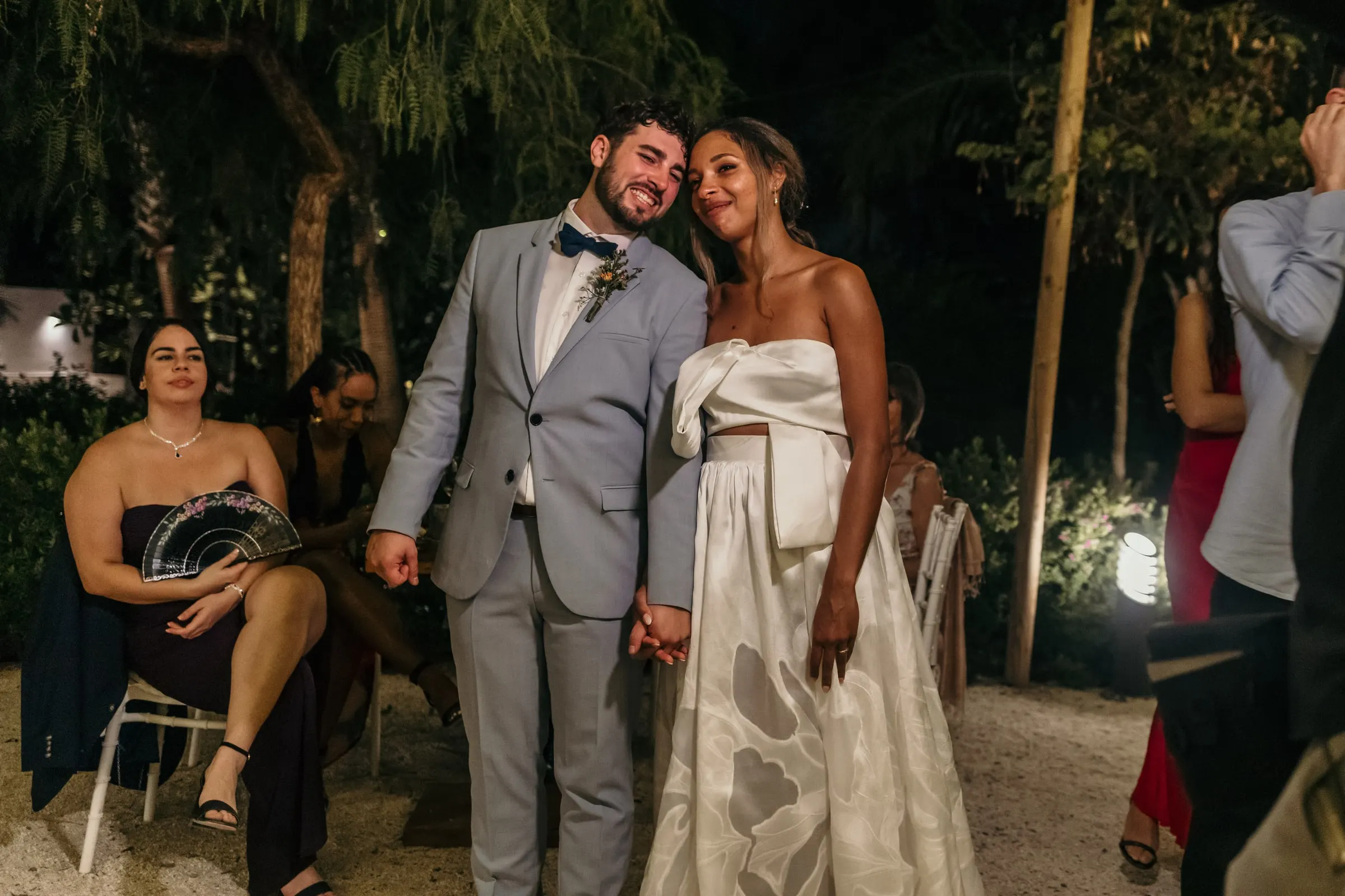 Los novios del brazo entre los invitados de noche en el jardín