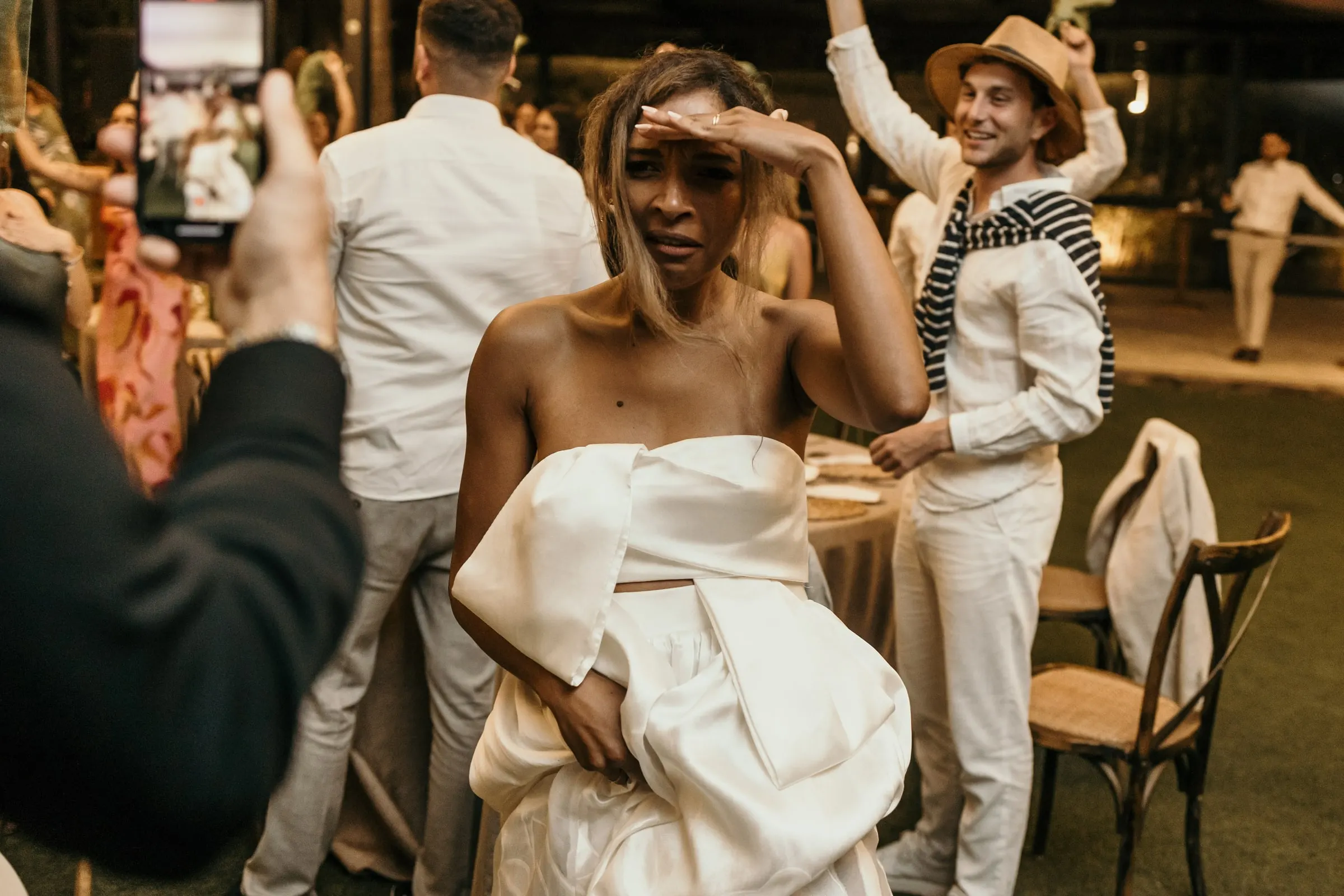 La novia se tapa los ojos en la pista mientras un invitado con sombrero de paja la jalea