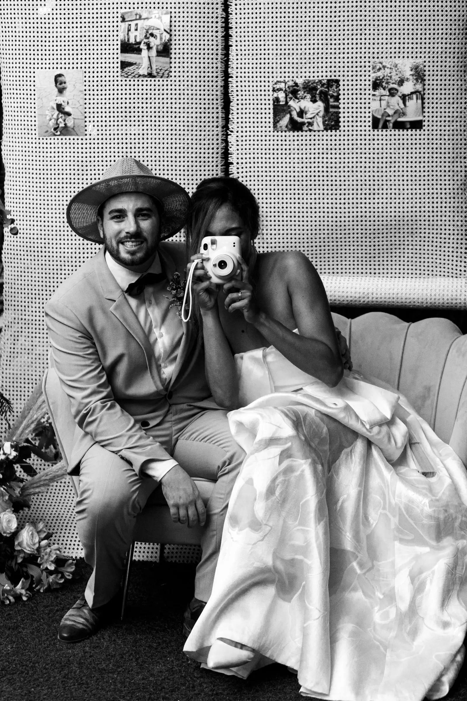 Foto en blanco y negro de los novios haciéndose una foto instantánea en el rincón de fotos