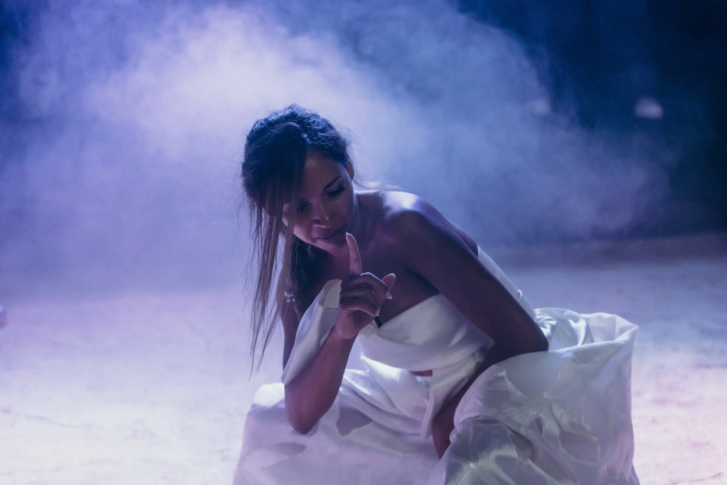 La novia baila entre humo bajo luz azul y violeta