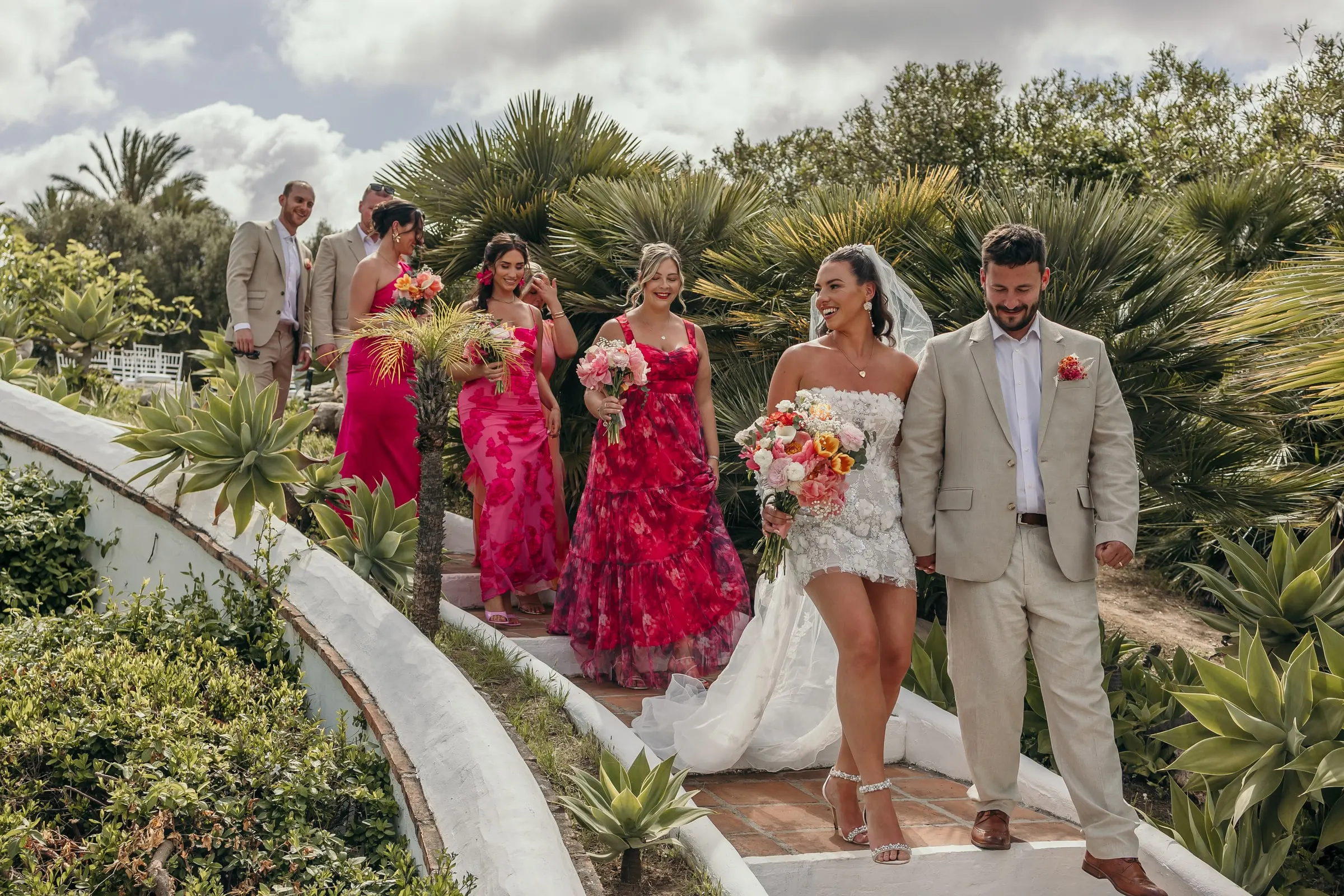 Los novios bajan por un camino curvo entre palmeras seguidos de las damas de rosa, Hacienda San José, Mijas