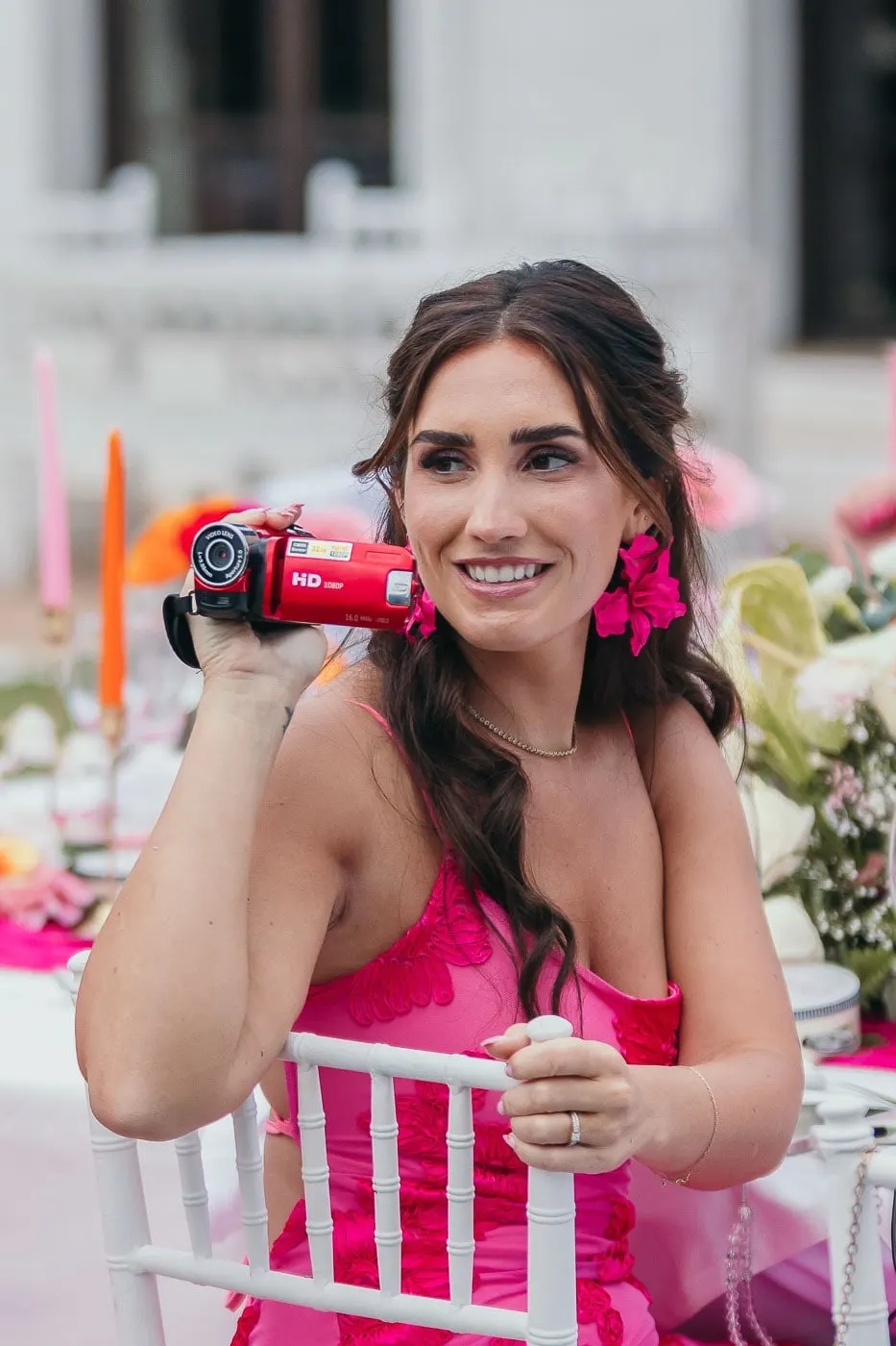 Guest in a pink dress filming the reception with a red handheld camcorder at the table, Hacienda San José, Mijas