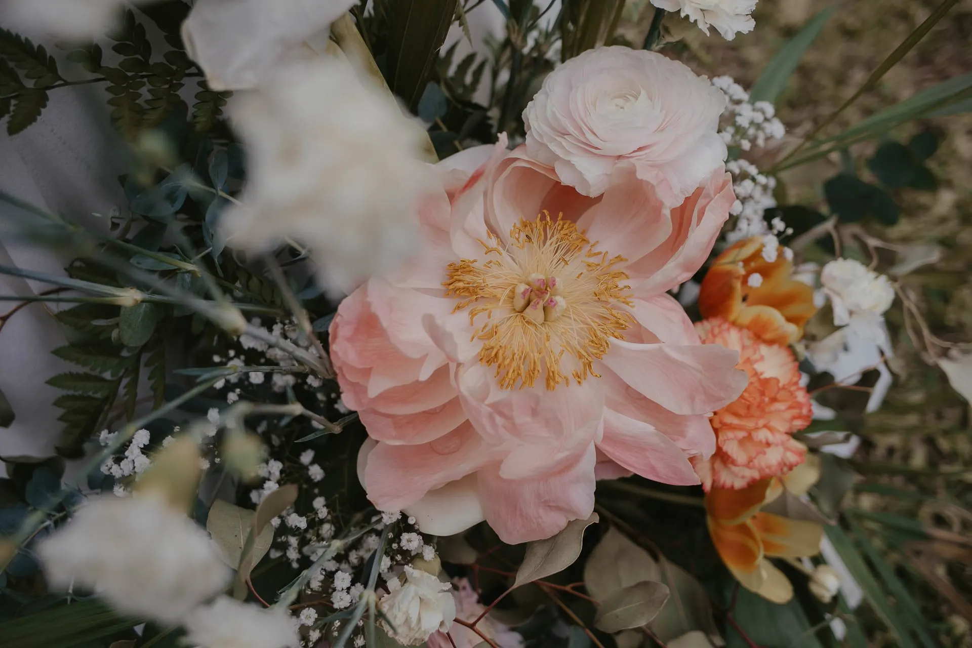 Close-up of the bridal bouquet with a pale pink peony, orange carnations and baby's breath, Hacienda San José, Mijas