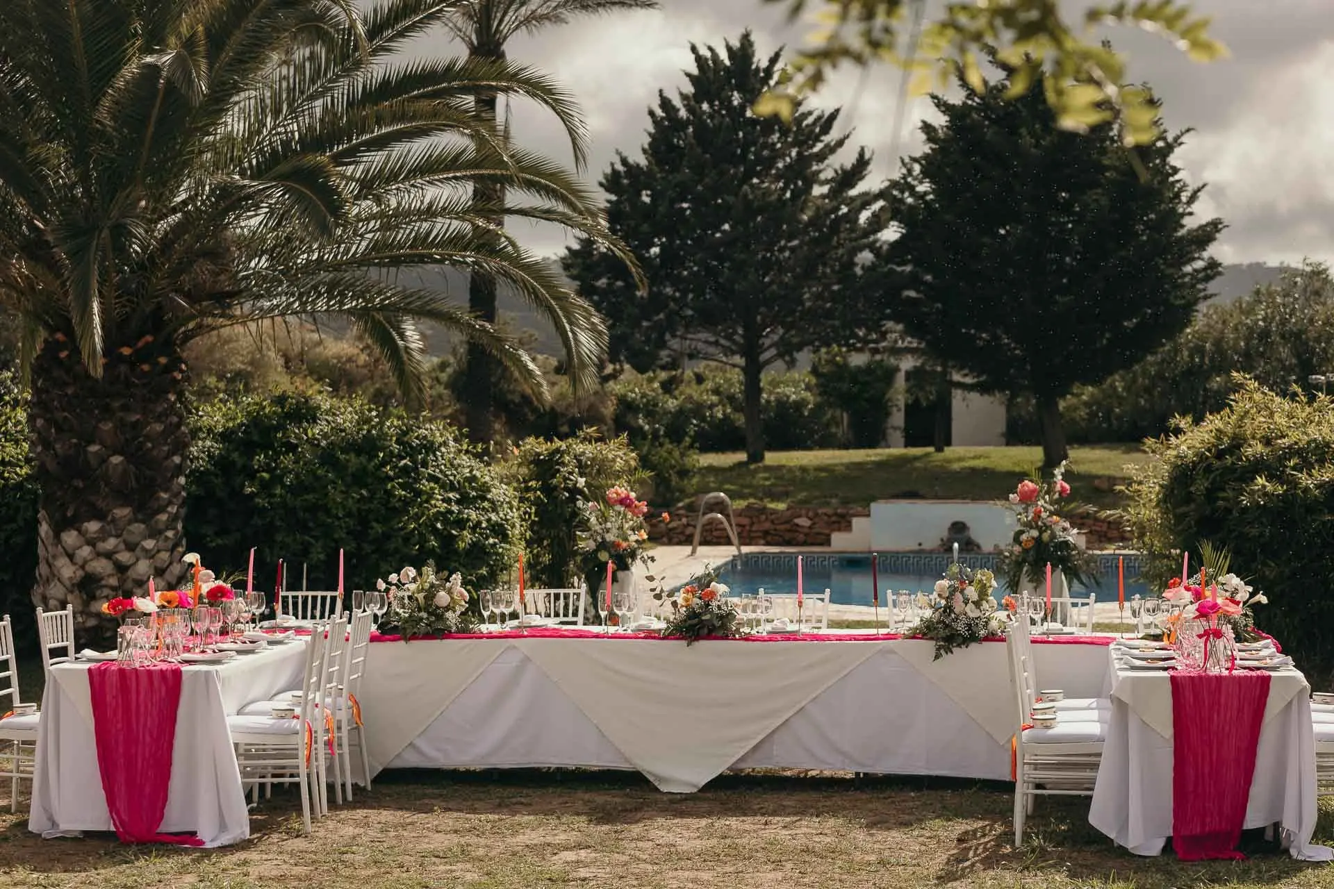 Long reception tables with pink runners and candles set by the pool among palms, Hacienda San José, Mijas