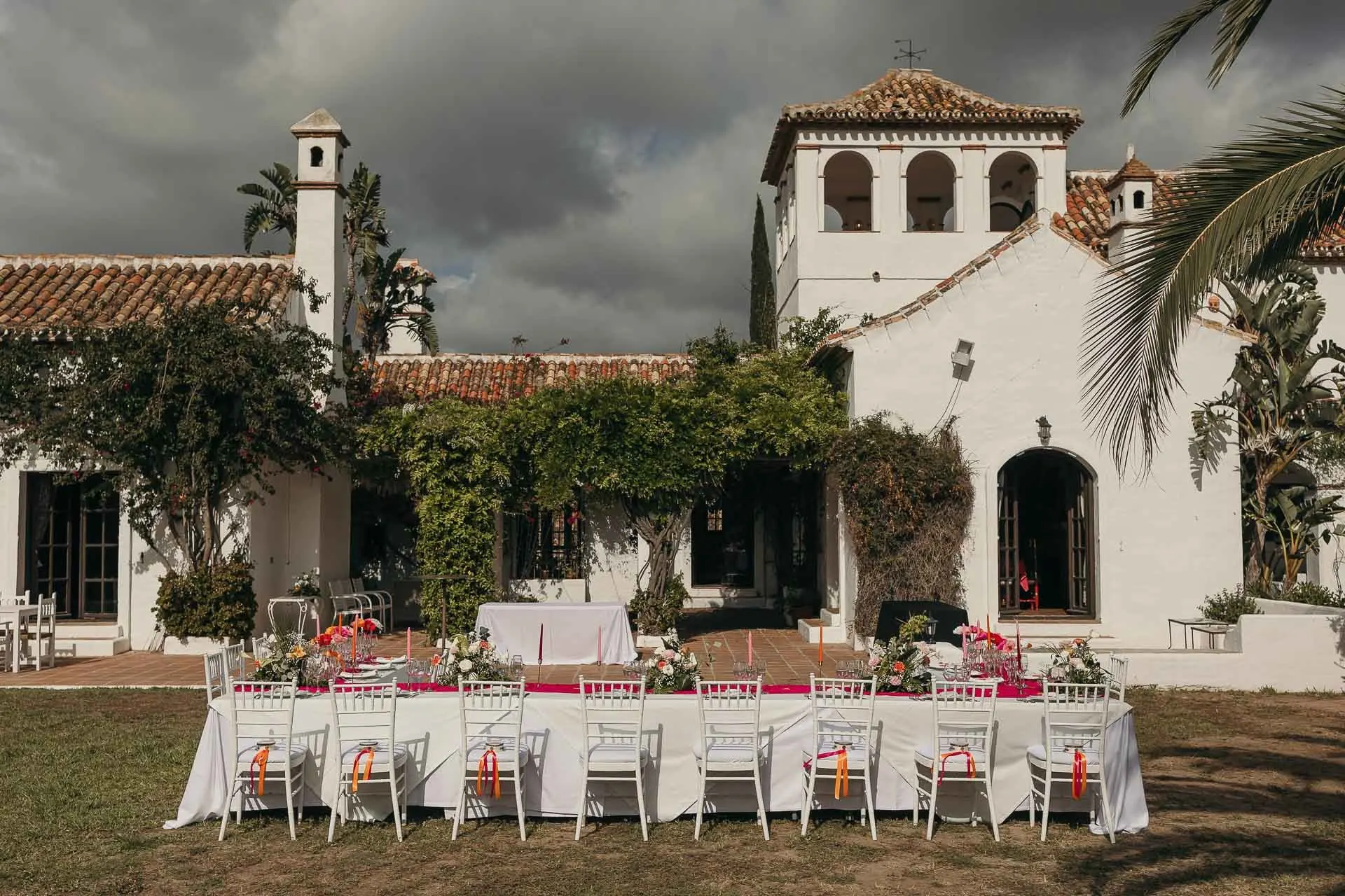 Reception tables laid on the lawn in front of the white bell-tower house, Hacienda San José, Mijas