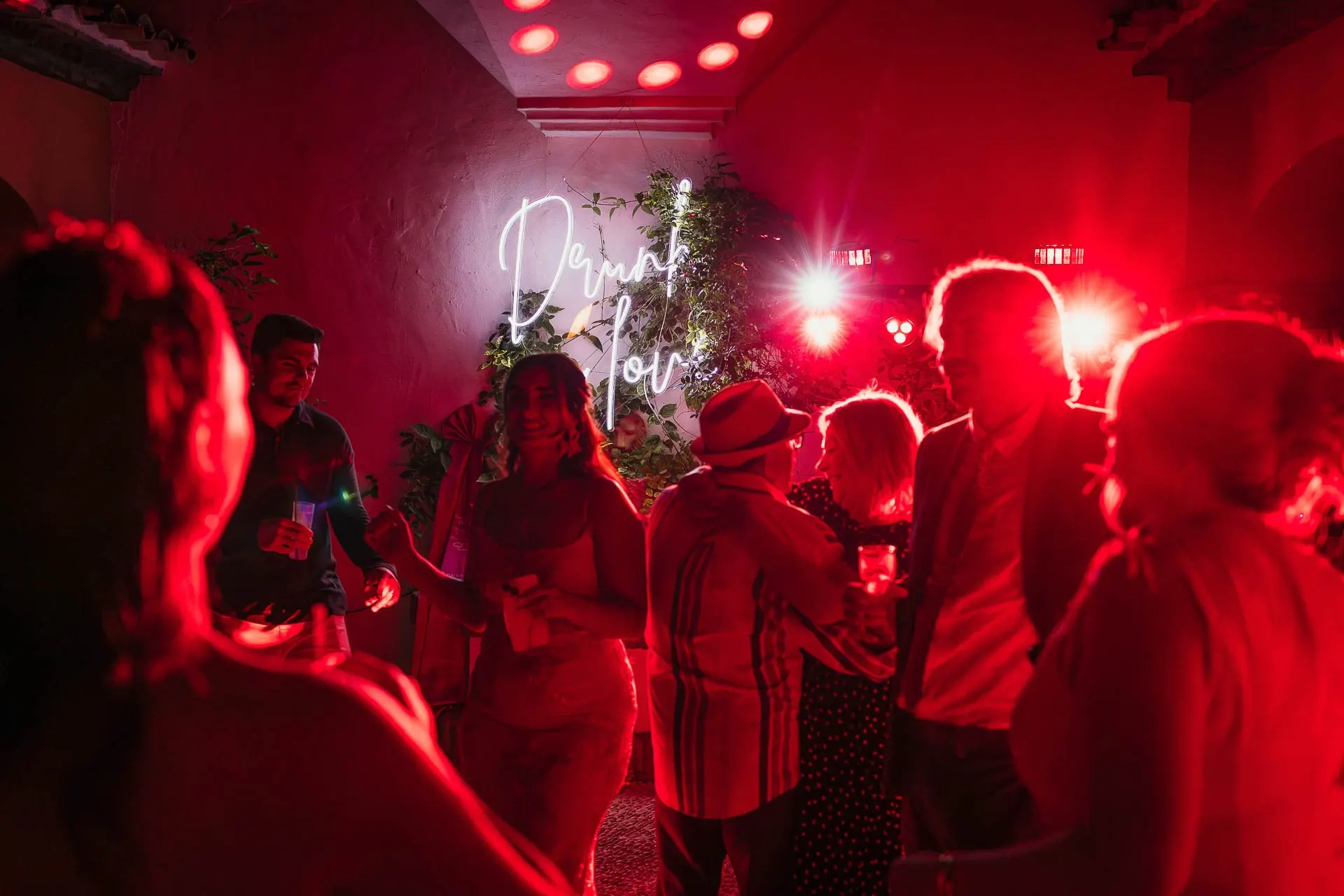 Guests dancing in red light in front of the neon sign at the evening party, Hacienda San José, Mijas