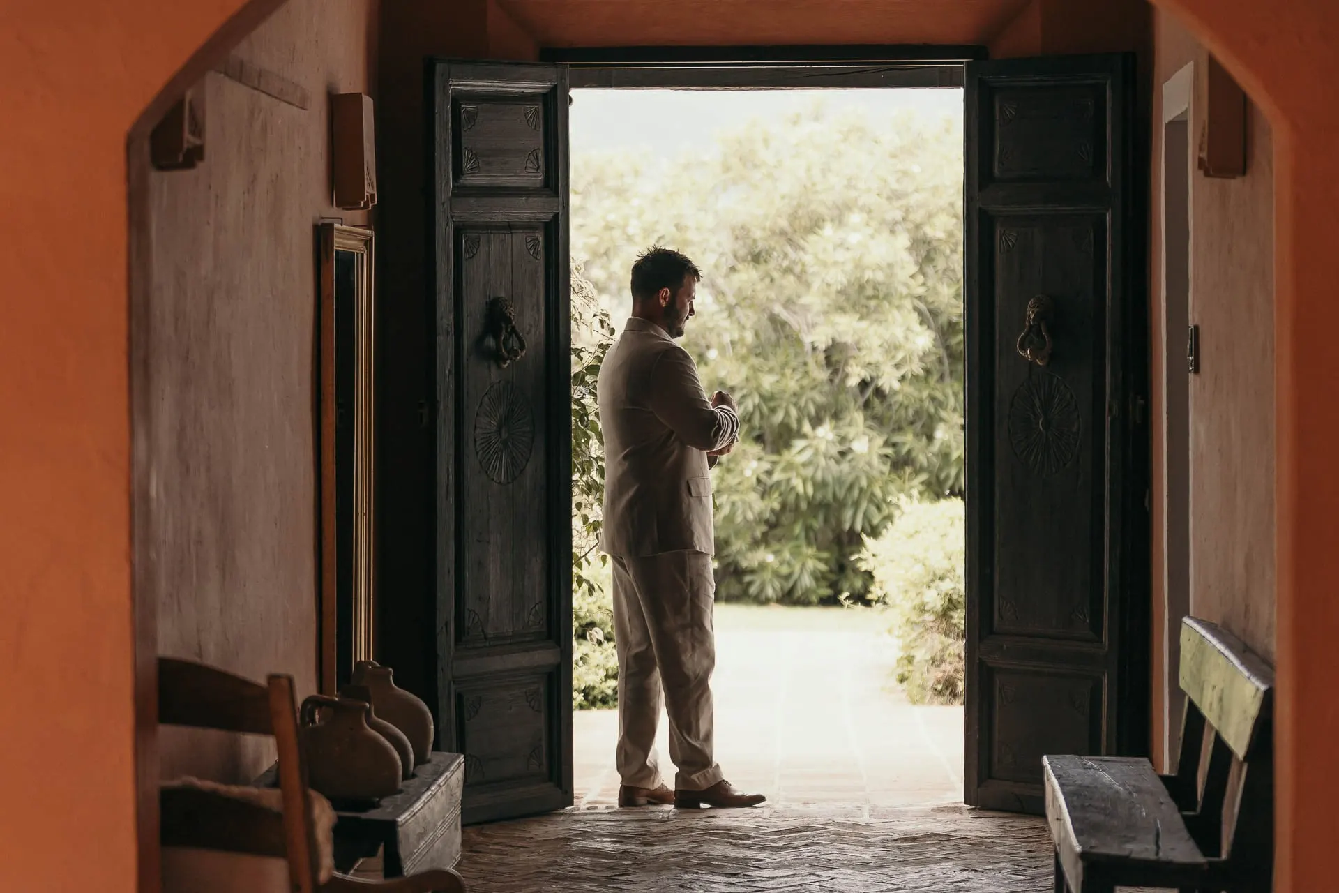 Groom silhouetted in an open double doorway looking out at the garden, Hacienda San José, Mijas