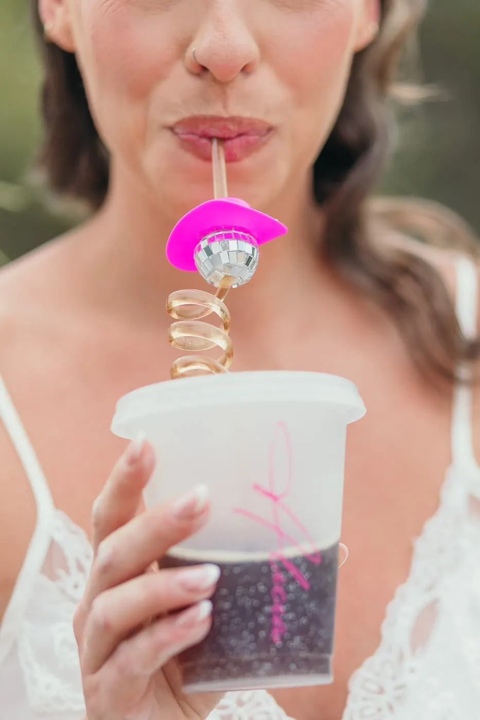 Bride sipping from a personalised cup with a pink disco-ball cowboy-hat straw, Hacienda San José, Mijas