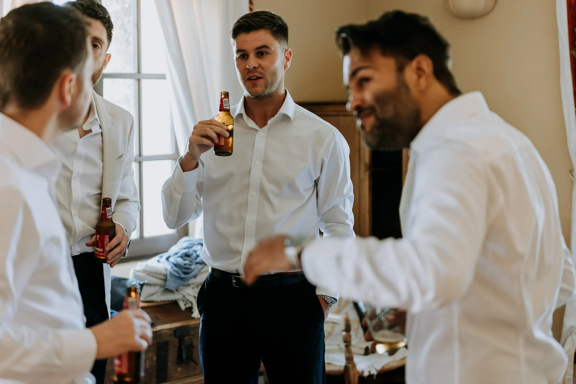 Groom and his friends in white shirts chatting with bottles of beer, Hacienda San José