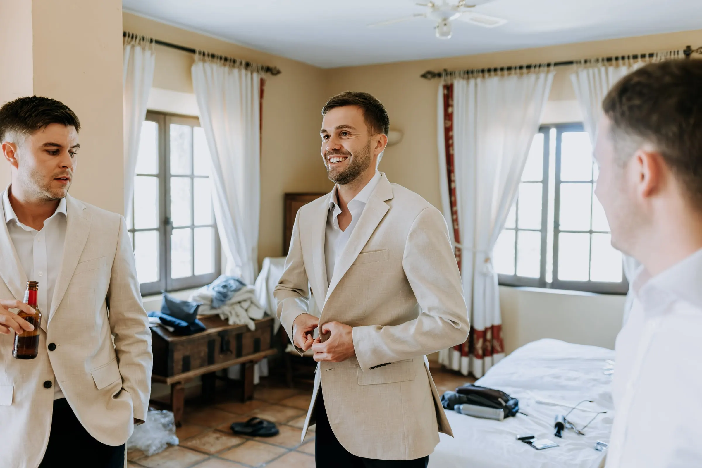 Groom in a beige linen jacket buttoning up among his friends, Mijas