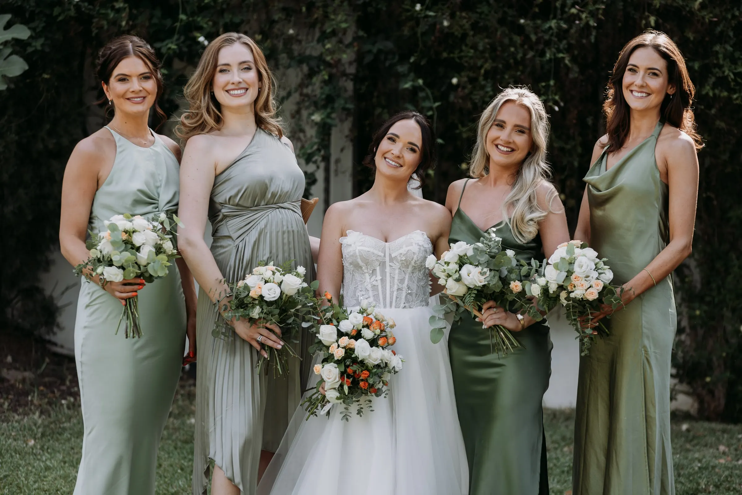 Bride with her bridesmaids in sage satin and their bouquets of white roses, Mijas