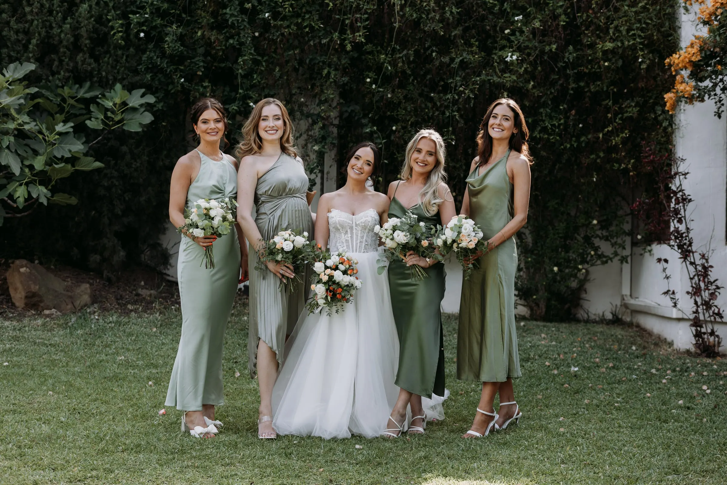 Bride and bridesmaids on the lawn beside a hedge of bougainvillea, Hacienda San José