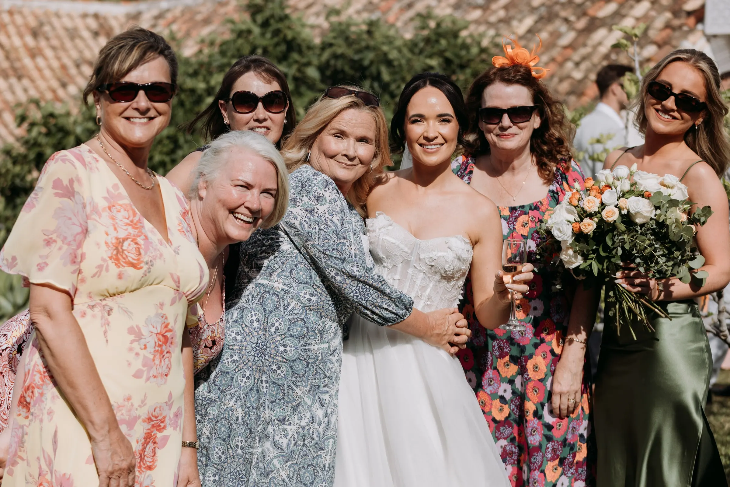 Bride hugged by friends and family in floral dresses at the drinks reception, Hacienda San José