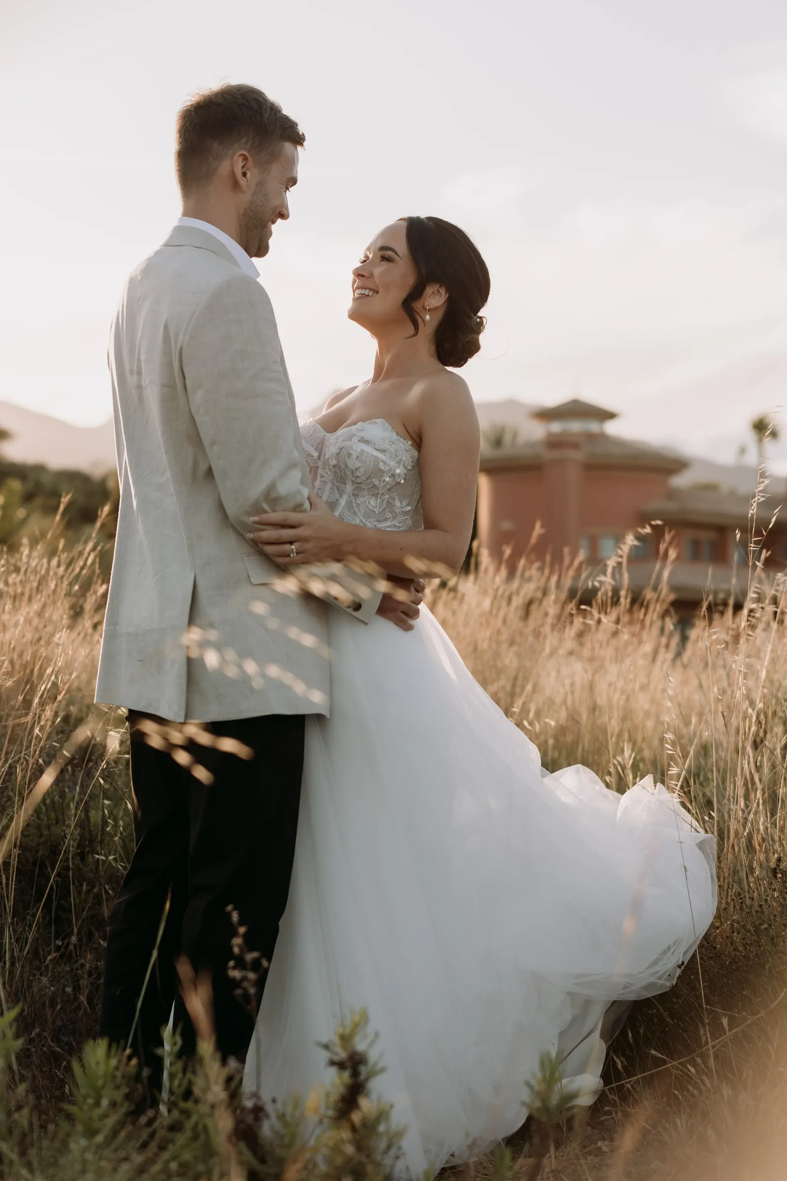 Bride and groom embracing in the long grass near Hacienda San José