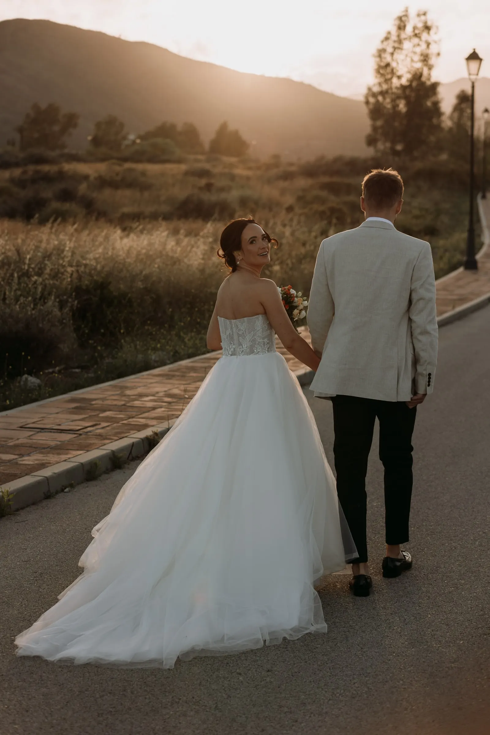 Bride and groom walking down a quiet road towards the sunset, Mijas