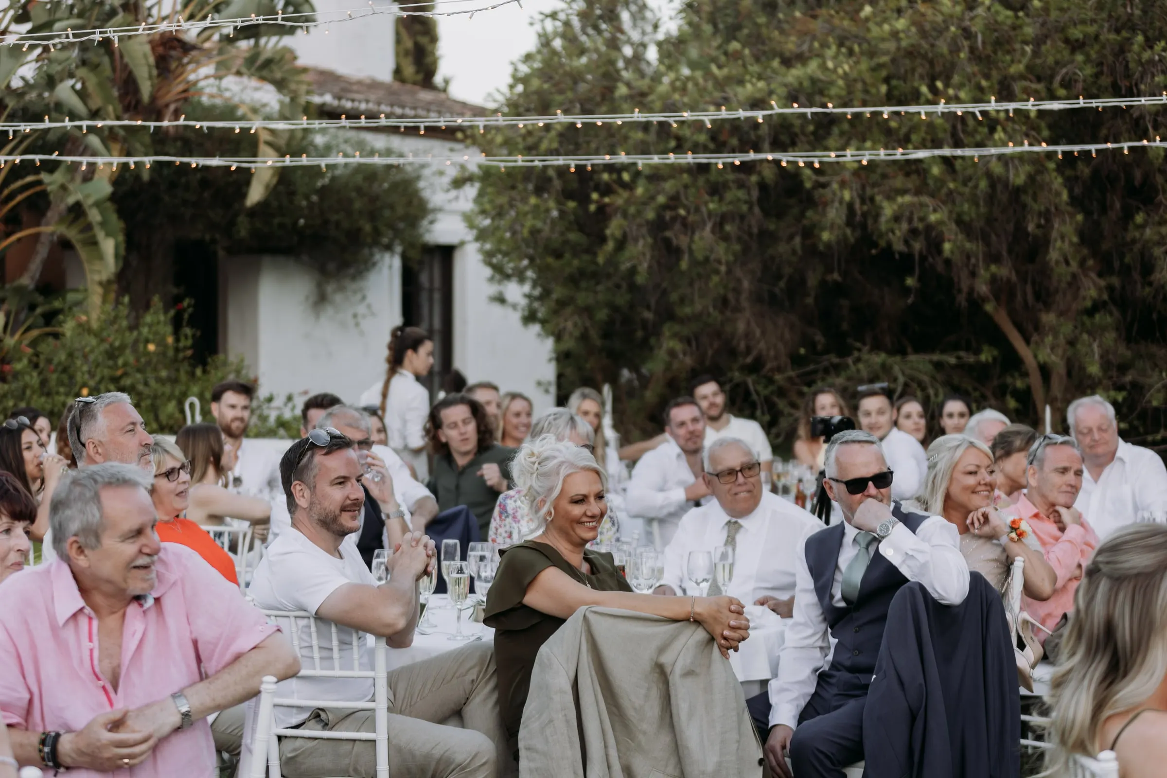 Guests laughing at the dinner tables under strings of lights, Hacienda San José