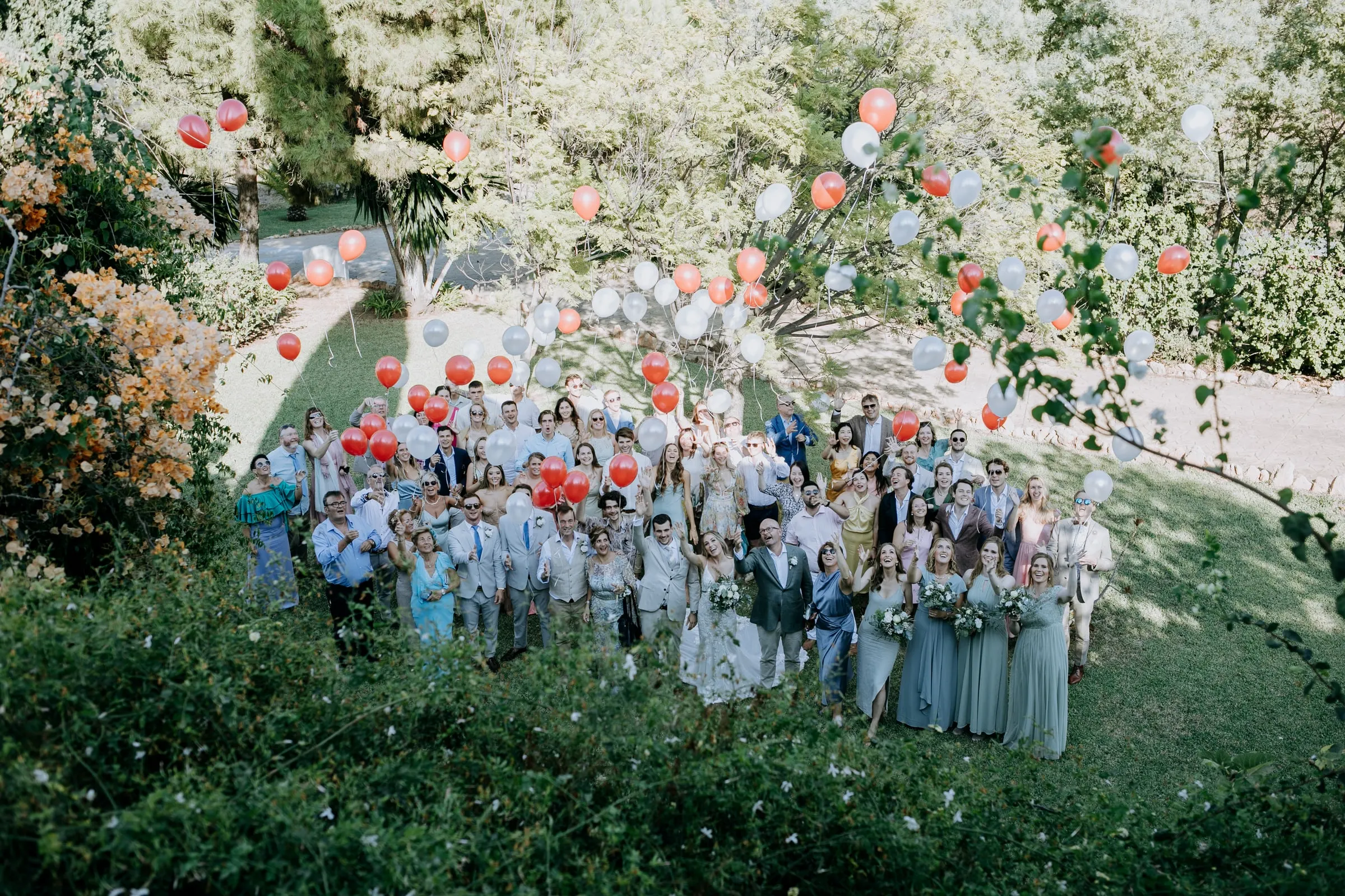 Todos los invitados posan en el césped soltando globos rojos y blancos, Hacienda San José, Mijas