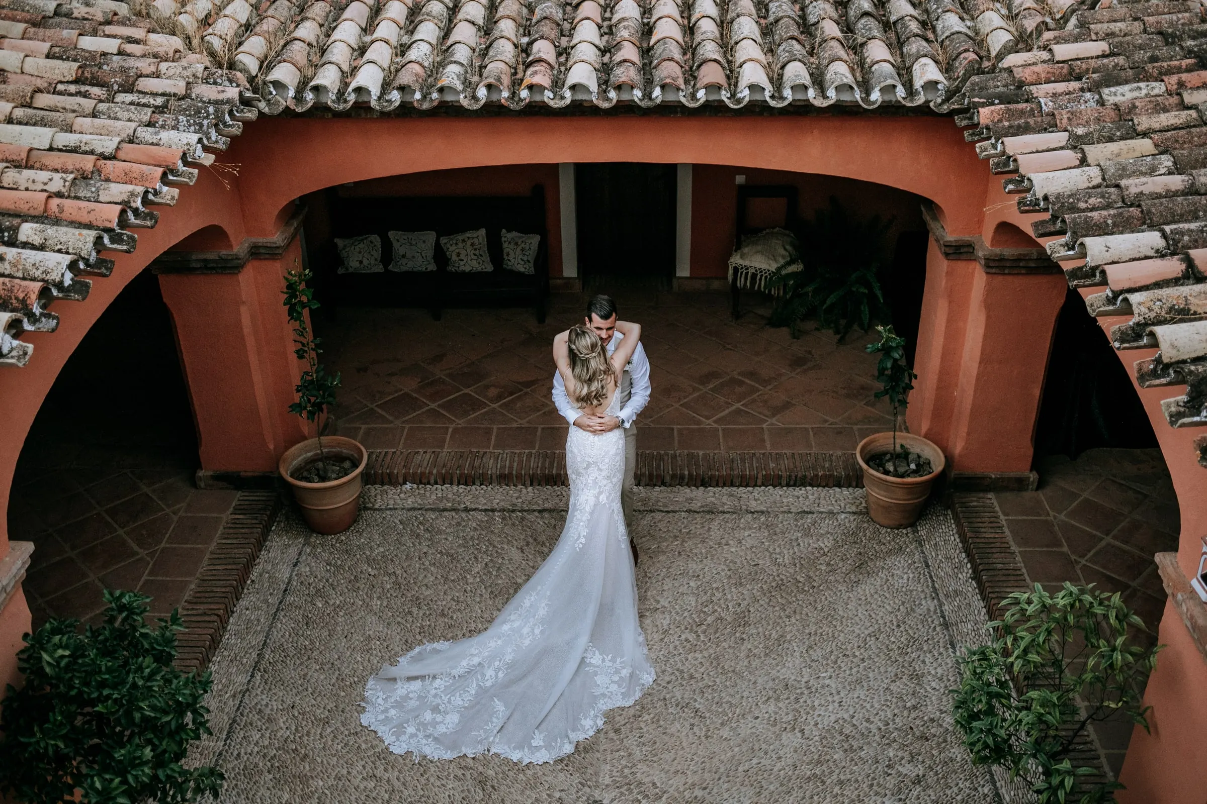 Los novios abrazados en el patio color teja visto desde arriba, con la cola extendida, Hacienda San José, Mijas