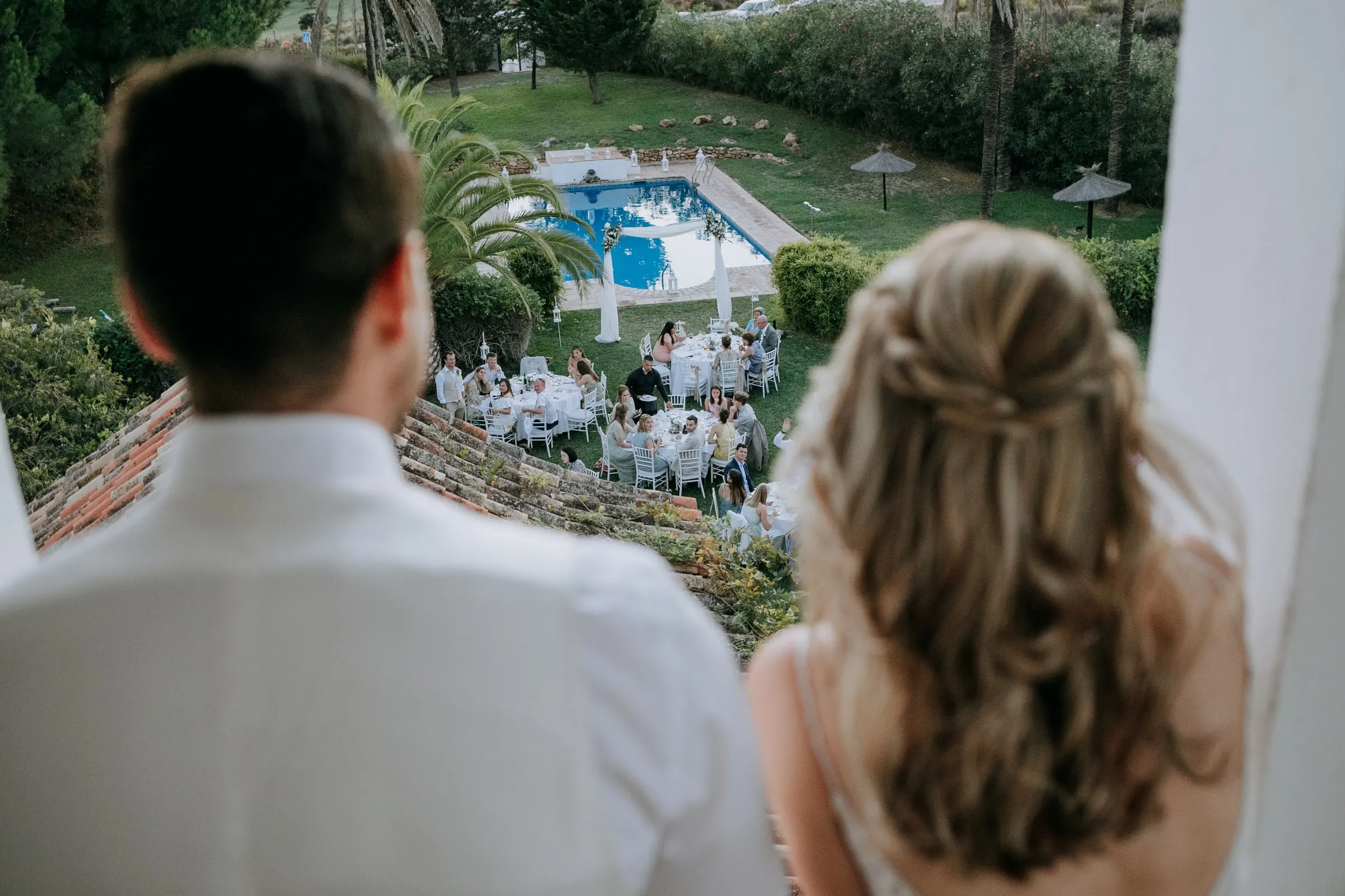 Los novios miran desde un balcón las mesas montadas alrededor de la piscina, Hacienda San José, Mijas